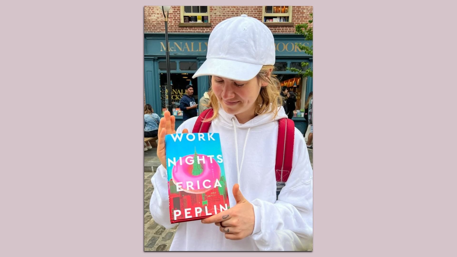 A photo of the author looking at her book. The cover is a giant donut on top of new york's skyline