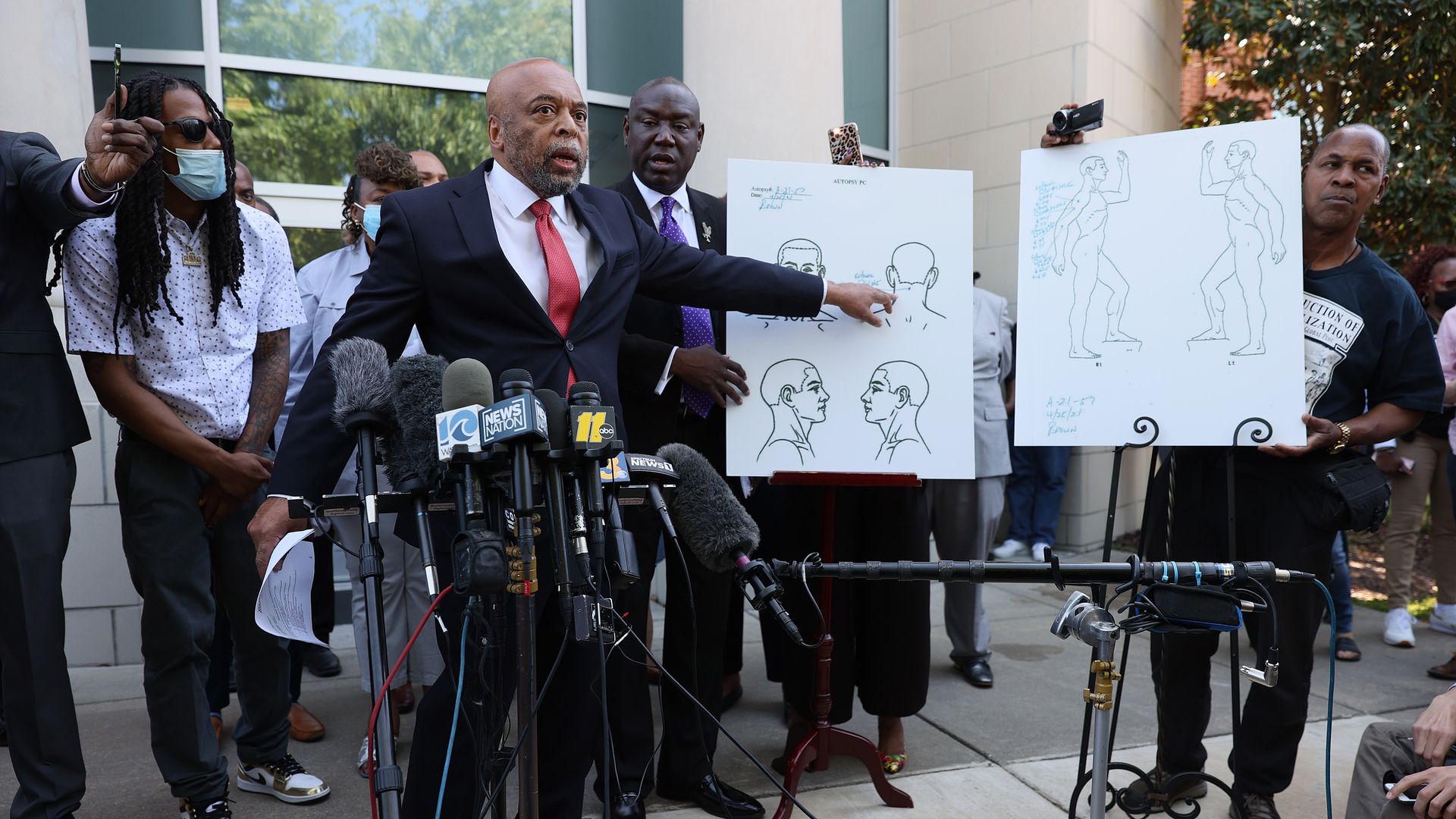 Photo of a person pointing to a poster showing a person's head and where they were shot