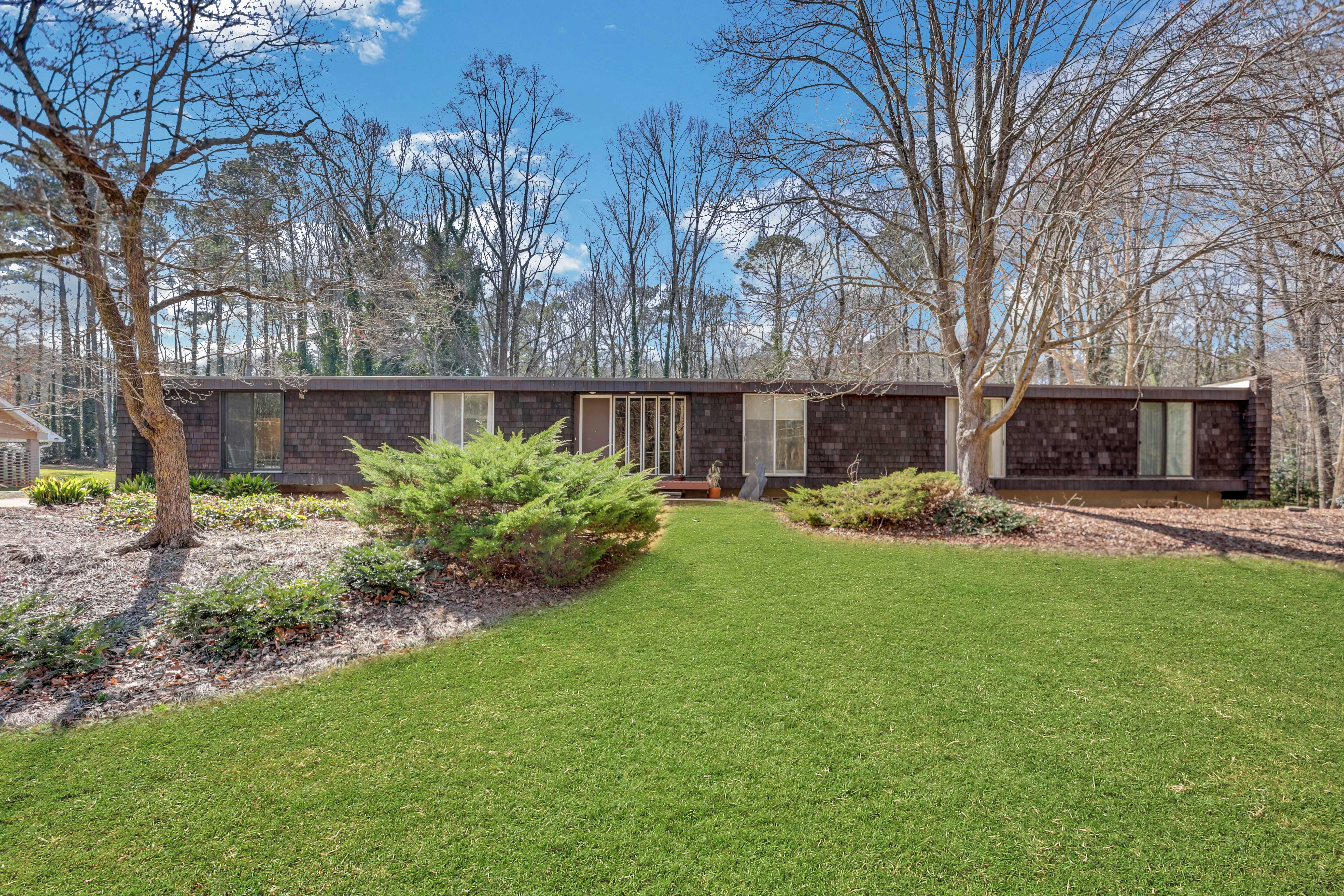 A one-story, simple mid-century modern home with a rich green front lawn