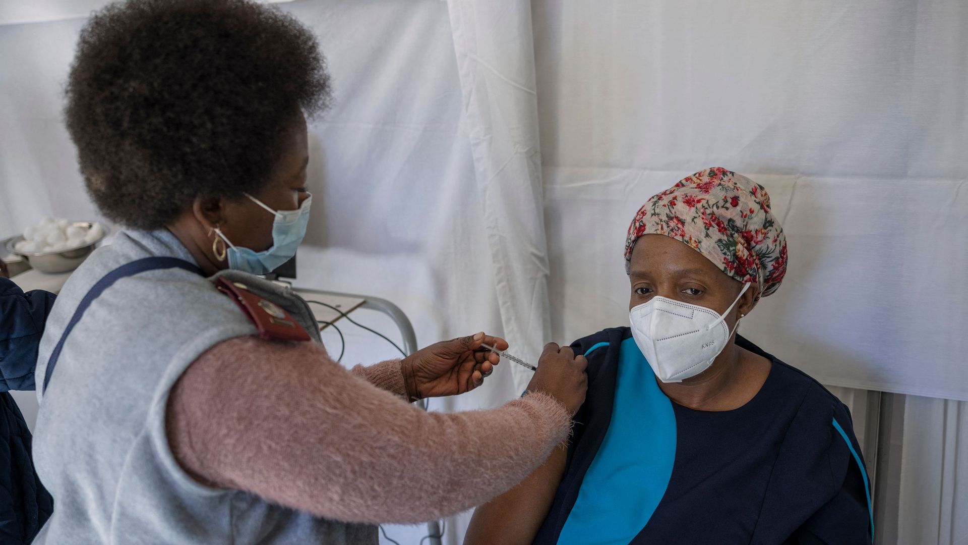 Photo of a health care worker giving a person sitting down a shot in the arm