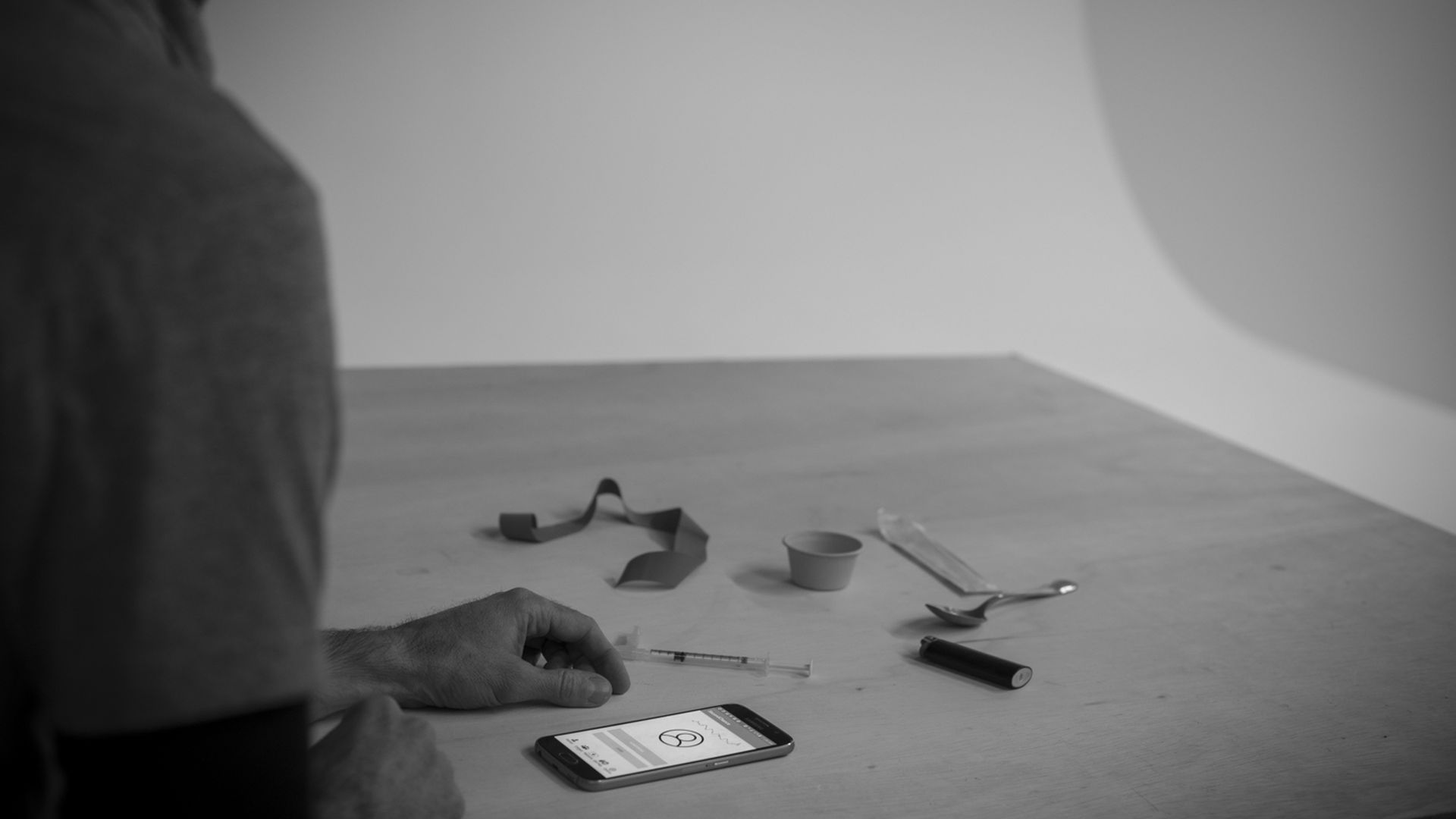 Photo of person using an opioid with their phone in front of them with the app on it