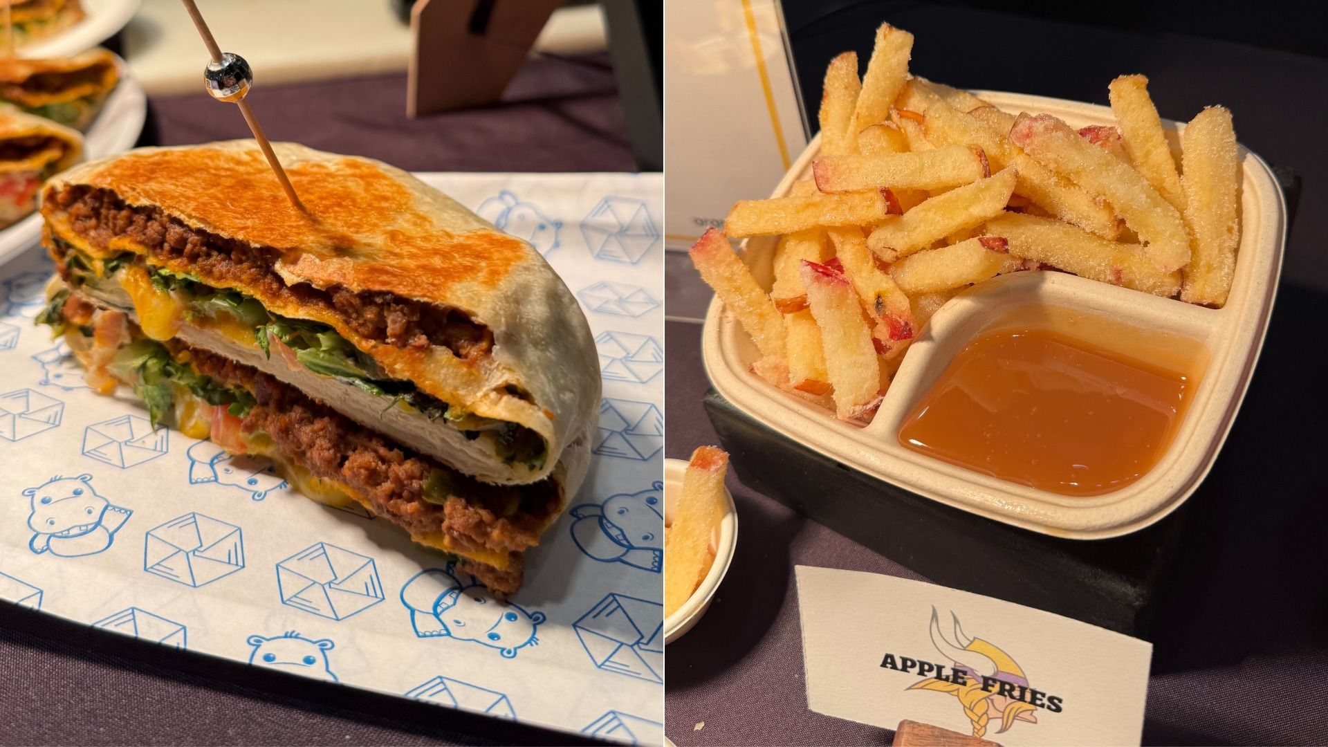 A close-up of a sandwich with ground meat, lettuce, cheese, and tomato in a toasted flatbread, alongside a serving of apple fries with a honey dip in a divided container.