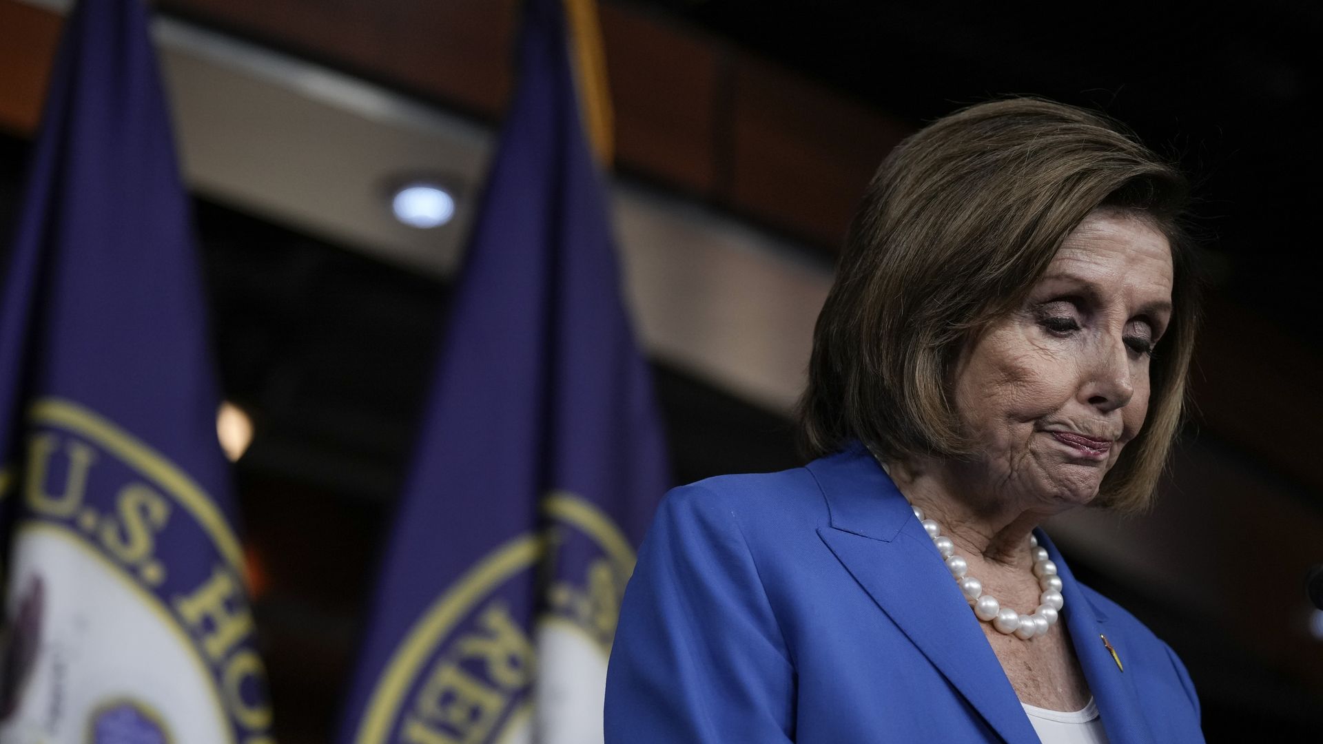 Photo of Nancy Pelosi looking down while speaking from a podium