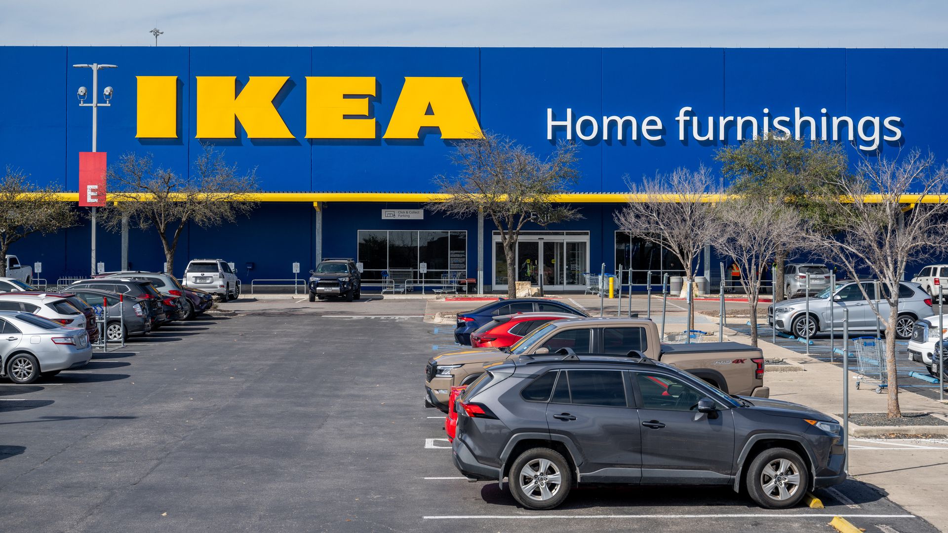 Photo shows a blue and yellow exterior of IKEA's store with cars parked in front.