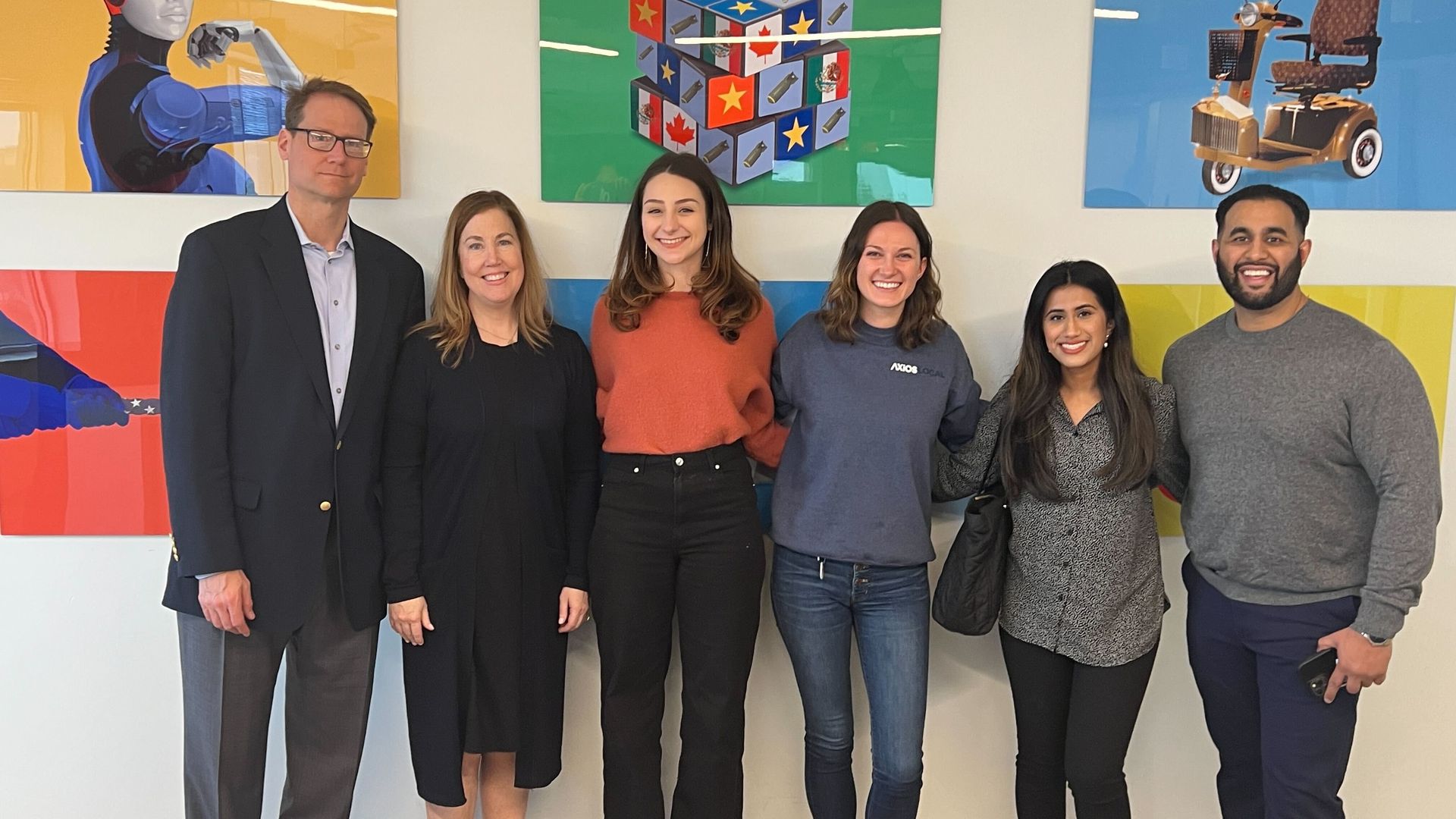 Two men and four women stand side by side in front of a mural.