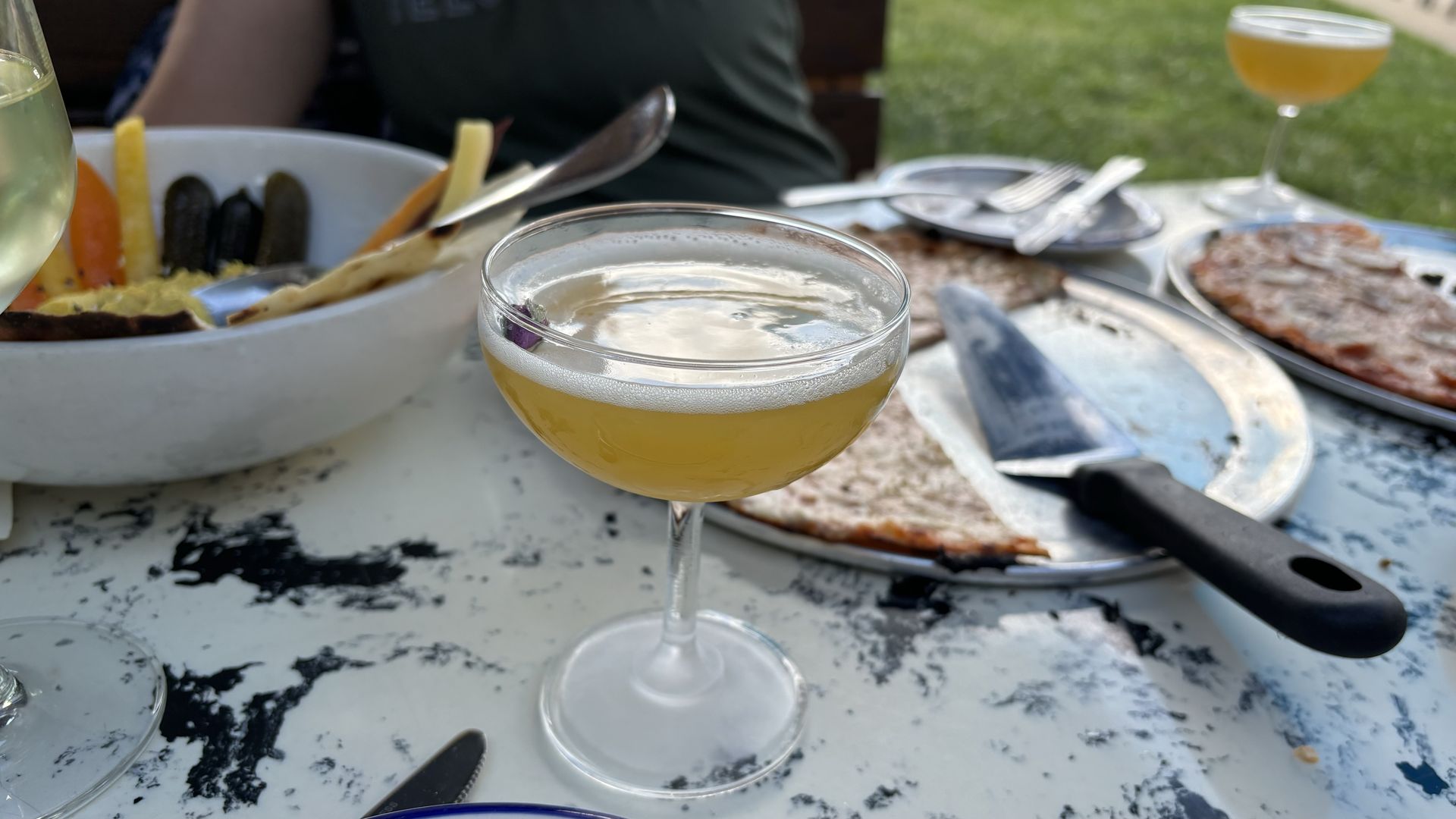 A drink on a table with pizza.