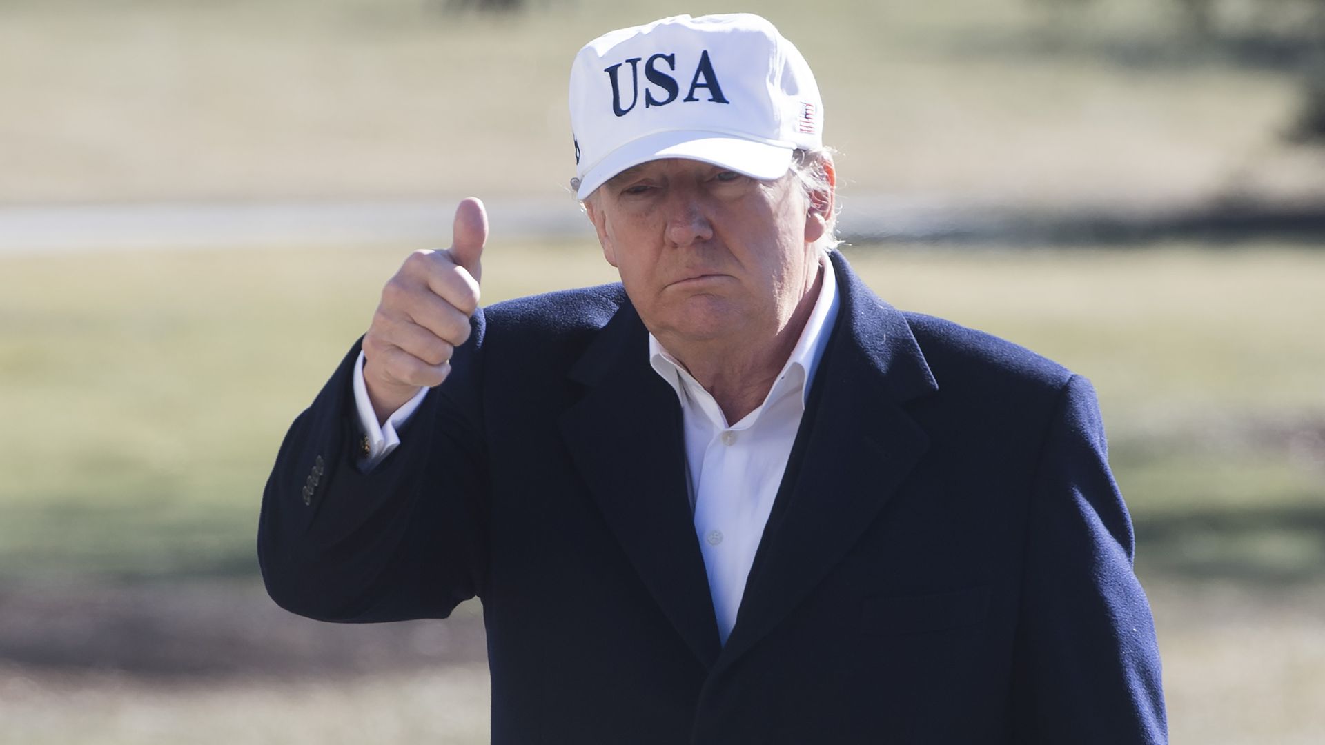 President Donald Trump wearing a USA hat giving a thumbs up