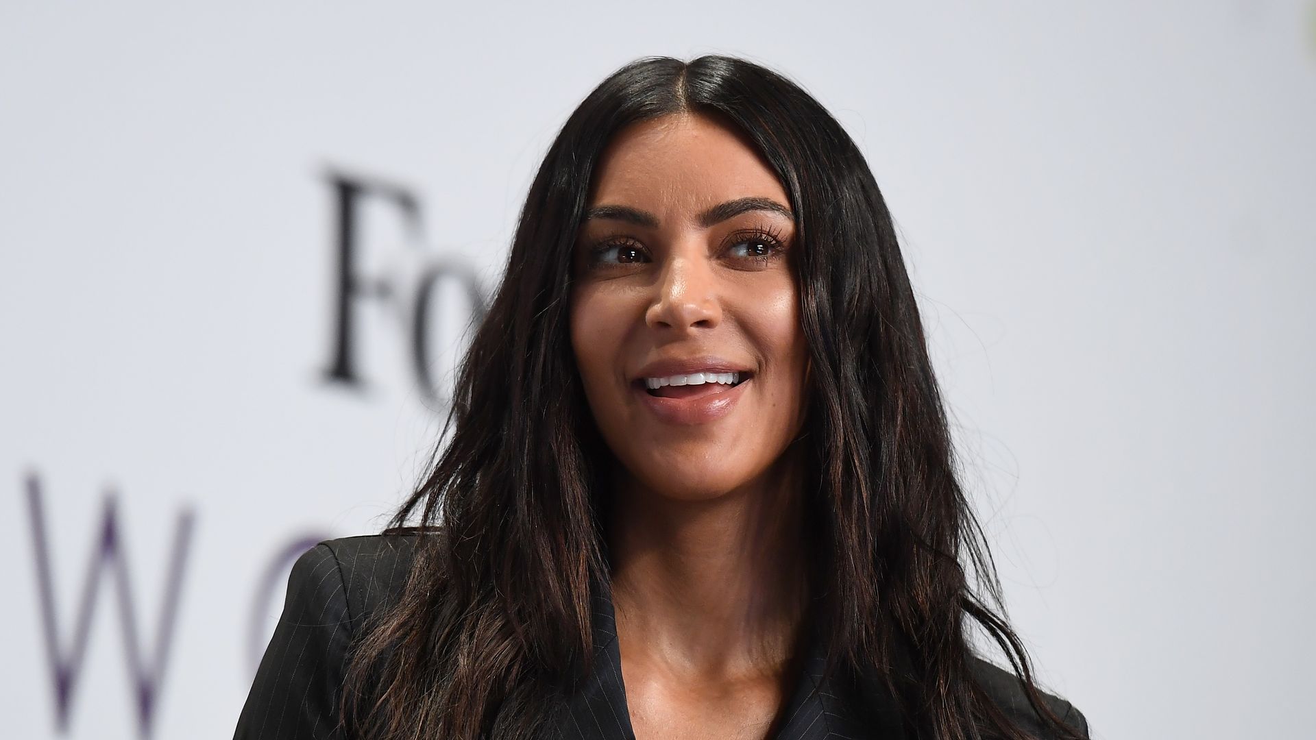Kim Kardashian in a black jacket smiling