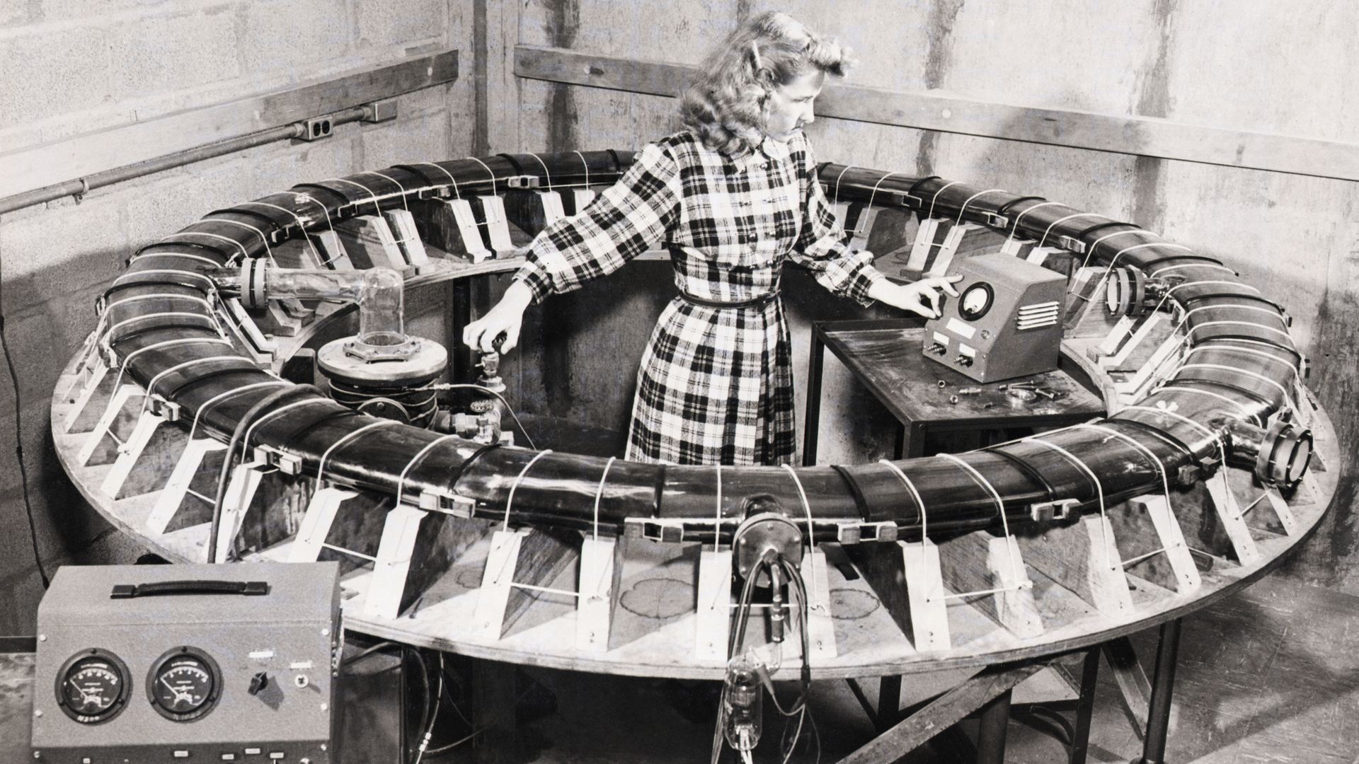 Black-and-white photo of a woman surrounded by a donut-shaped tube in a lab