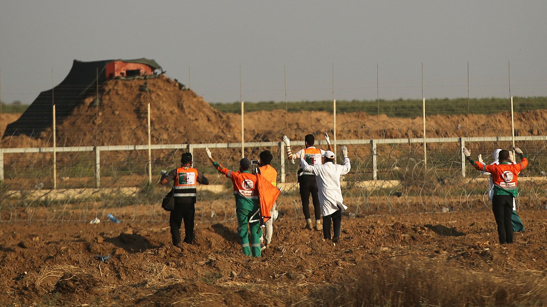 medical workers approach Israeli-Gaza border fence with arms up