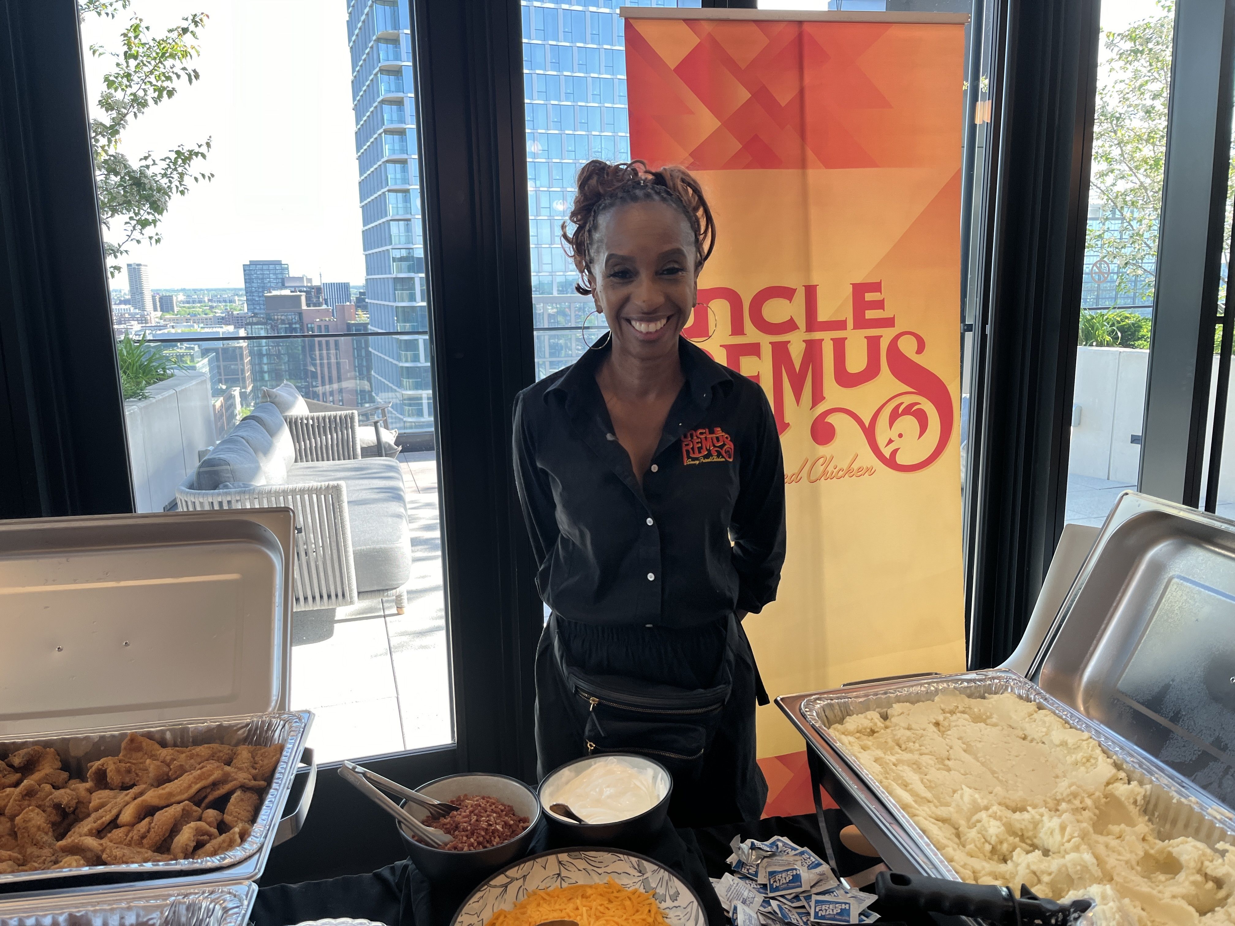Photo of a woman standing in front of trays of food 