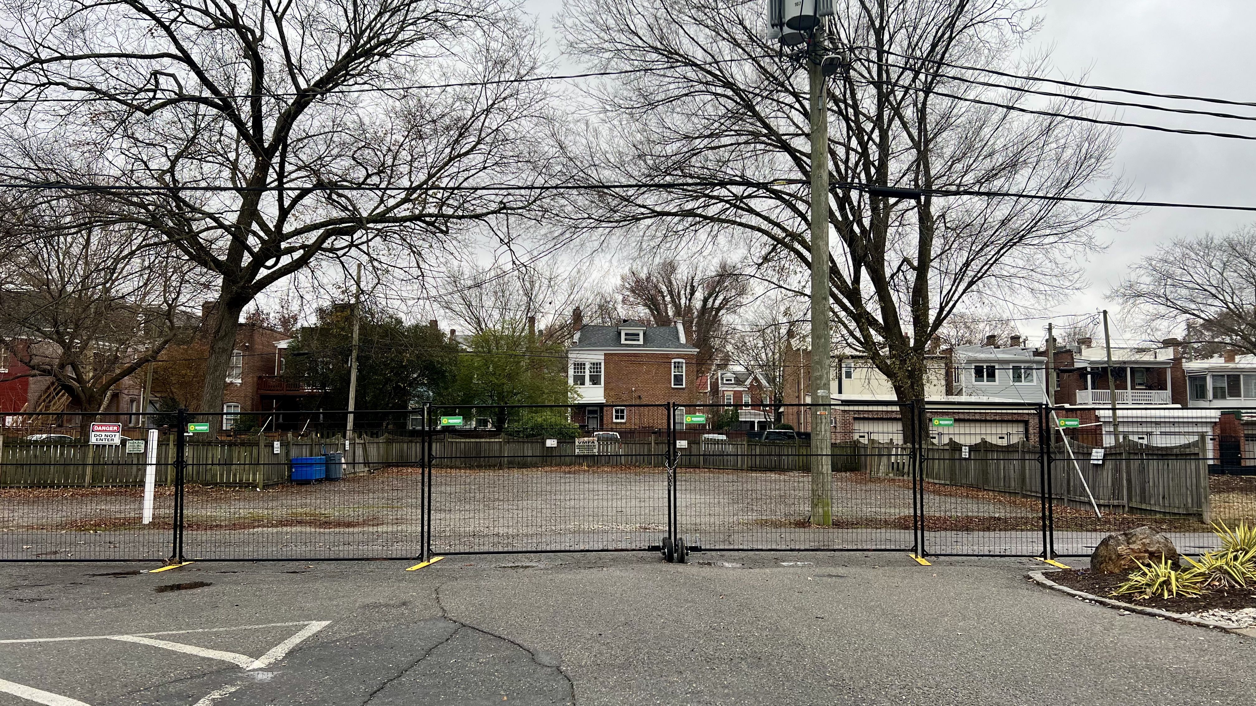 a fence in a parking lot with houses behind it