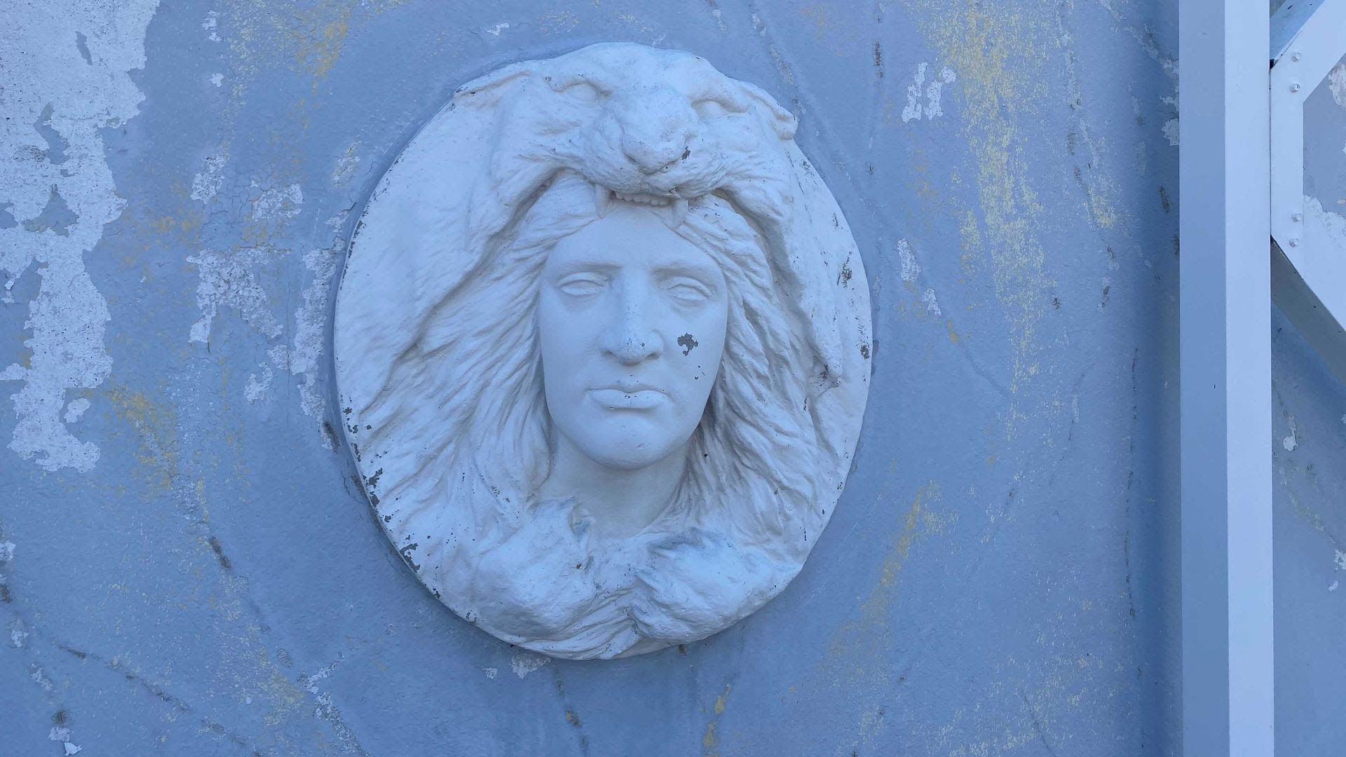 A stone fixture of a person with a panther on their head