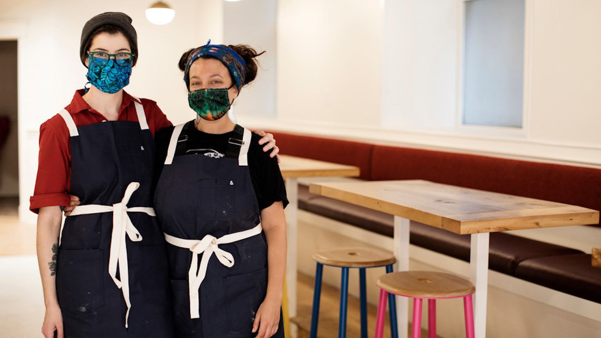 The owners of Hark! Cafe stand arm in arm in their Minneapolis restaurant.