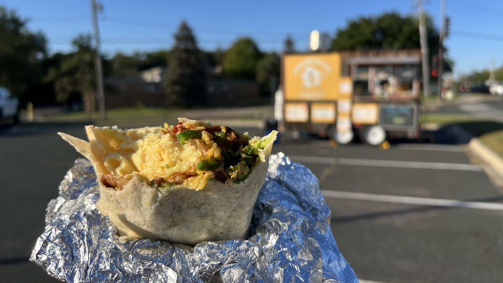 A close-up image of a half-eaten breakfast burrito in its foil wrapper