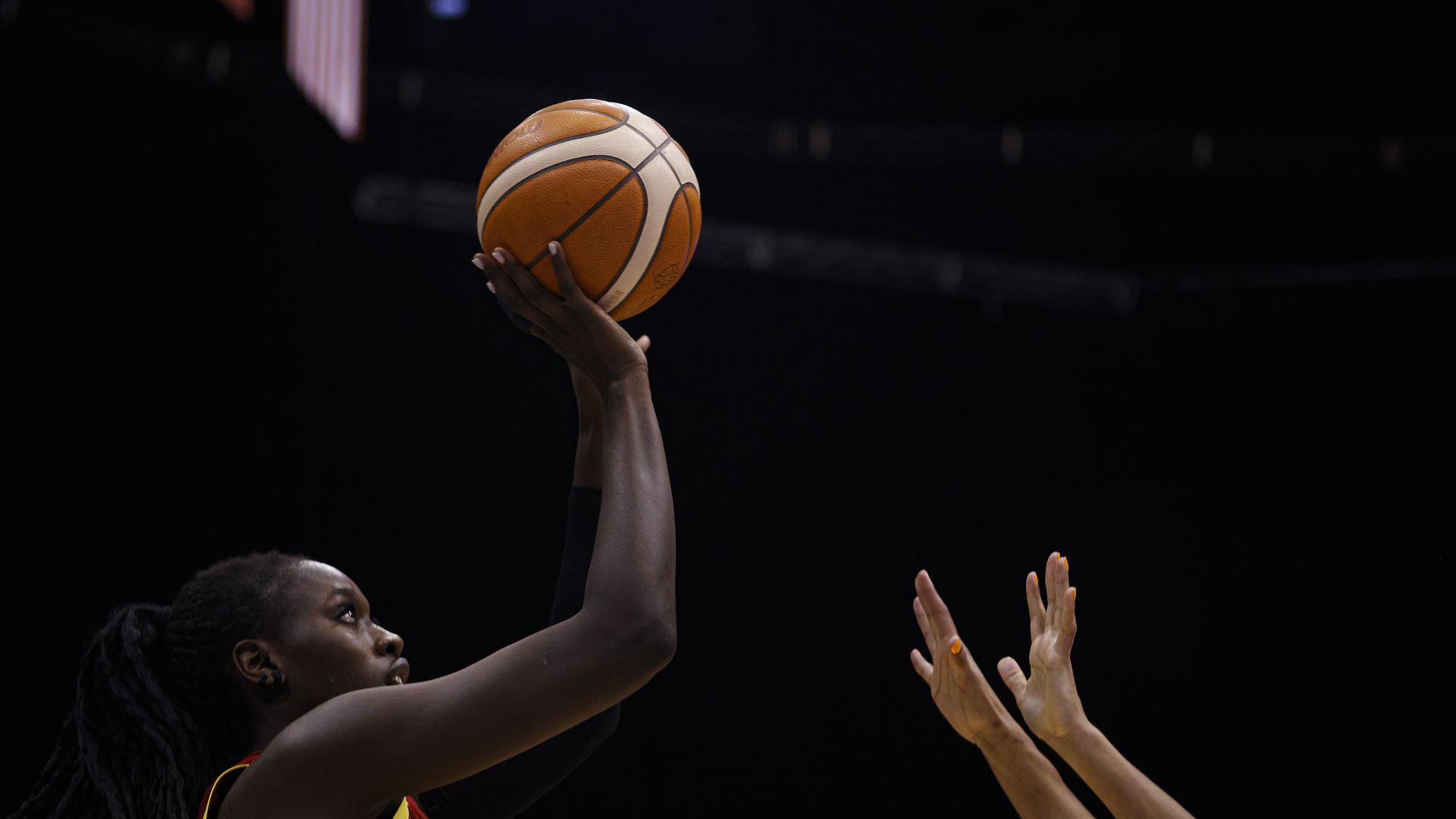 A professional female basketball player holds the ball up ready to shoot.