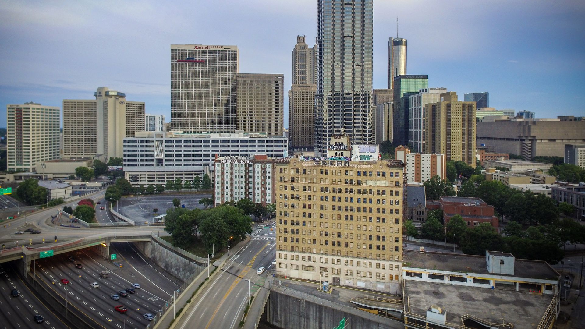 A photo of the Medical Arts Building with broken and boarded-up windows with Downtown Atlanta in the background and the interstate in the foreground