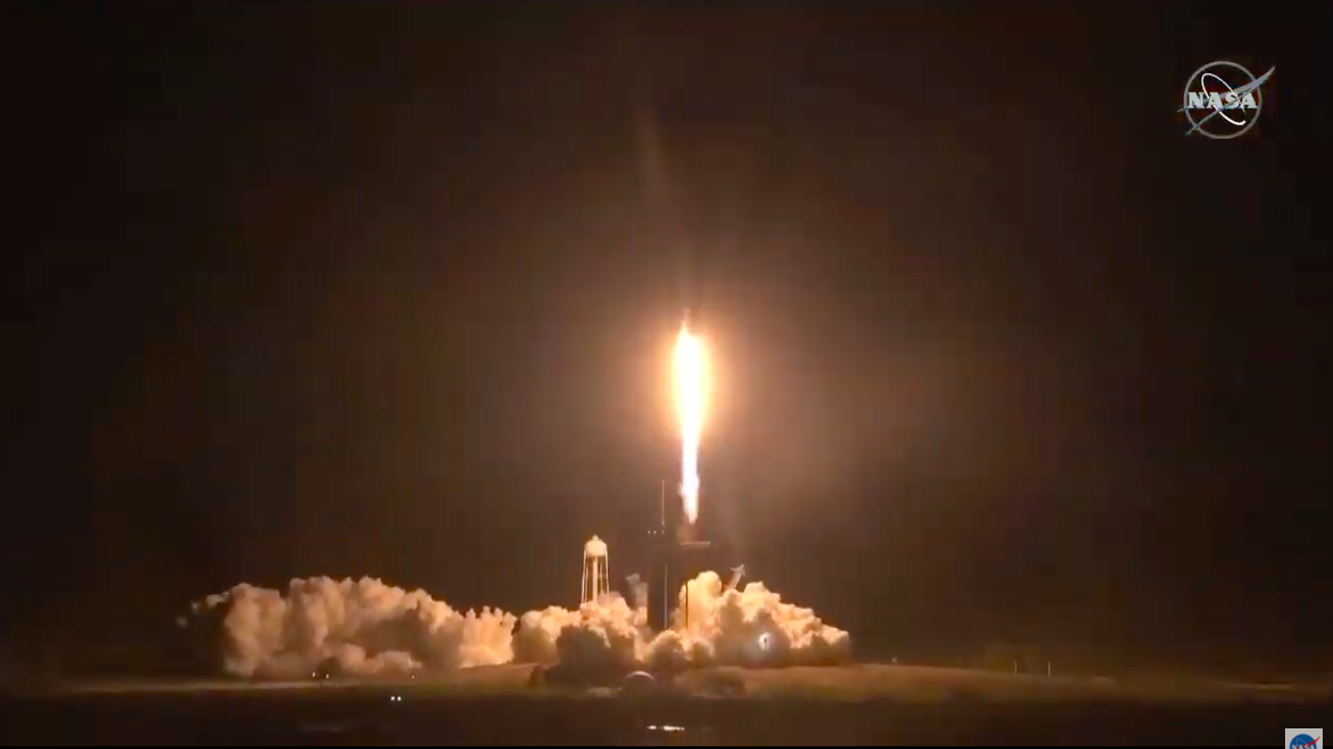 A Falcon 9 rocket carrying four crewmembers lifts off at night to the International Space Station