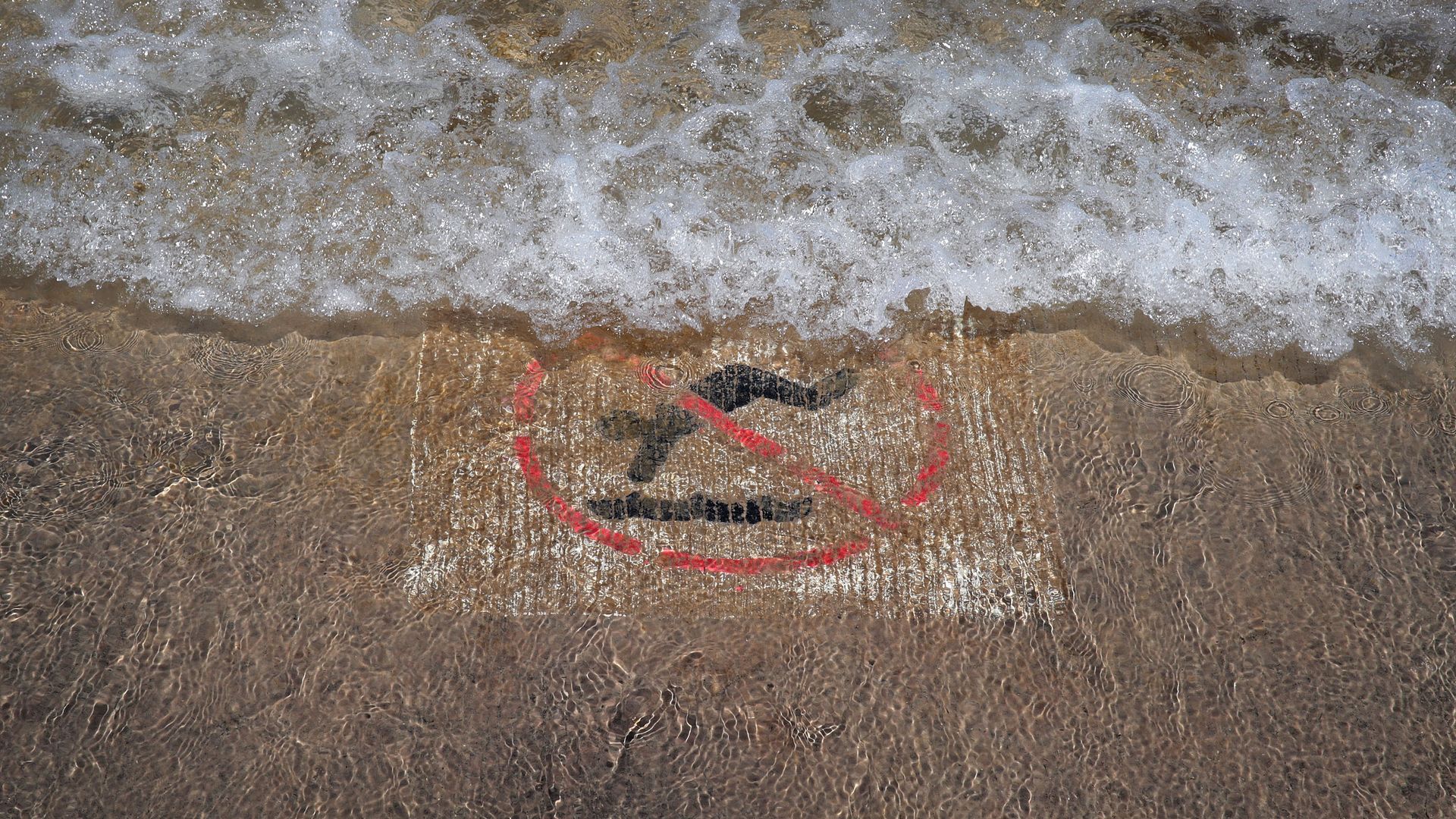 Waves wash over a concrete bike and jogging path along Lake Michigan