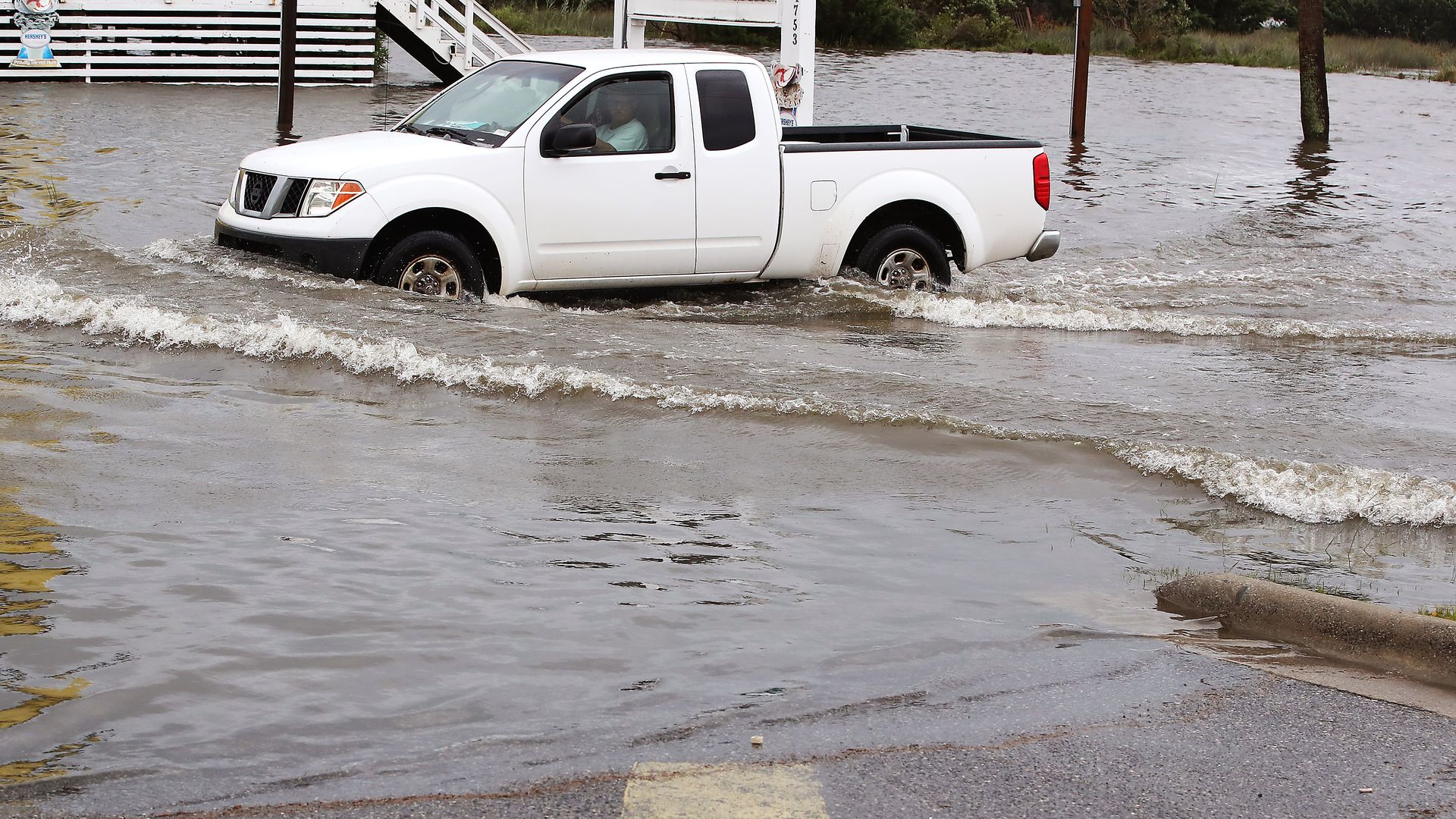 In this image, a truck drives through a few feet of water on a road.