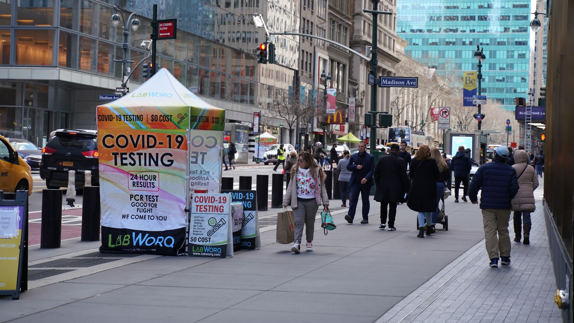 Photo of a COVID testing booth set up along a NYC street as people walk by