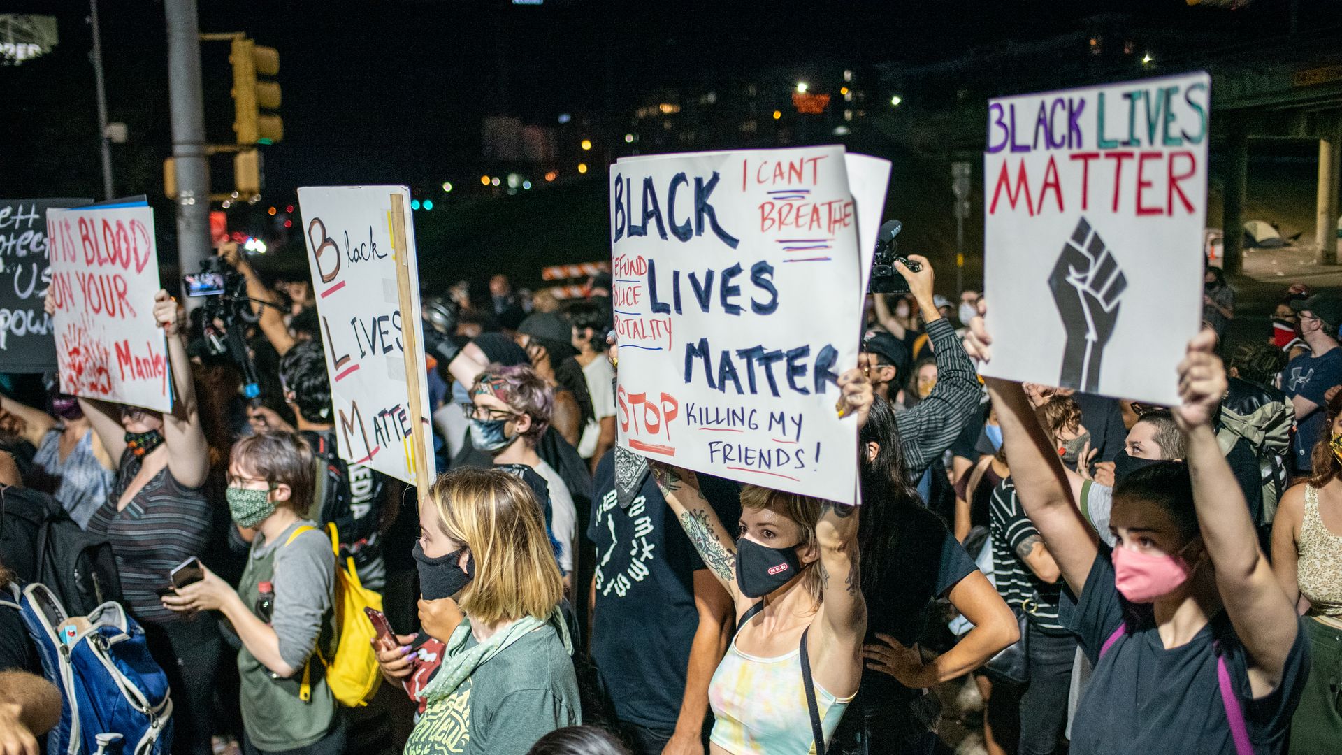 Rows of protesters wearing masks and holding up signes that say "black lives matter" march in Austin 