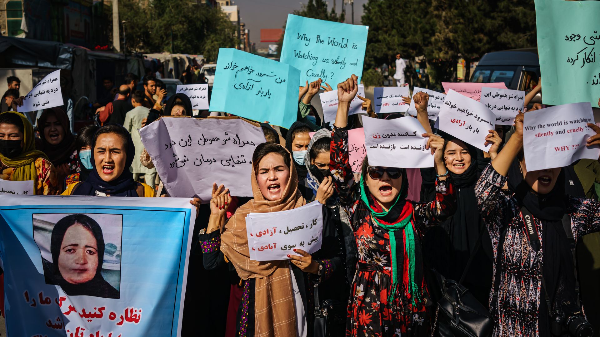 Photo of a group of Afghan women holding signs and protesting the Taliban's strict rule