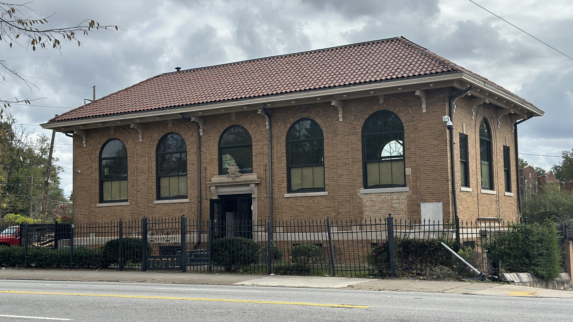 A historic rectangular brick building with large arched windows and terra cotta roof