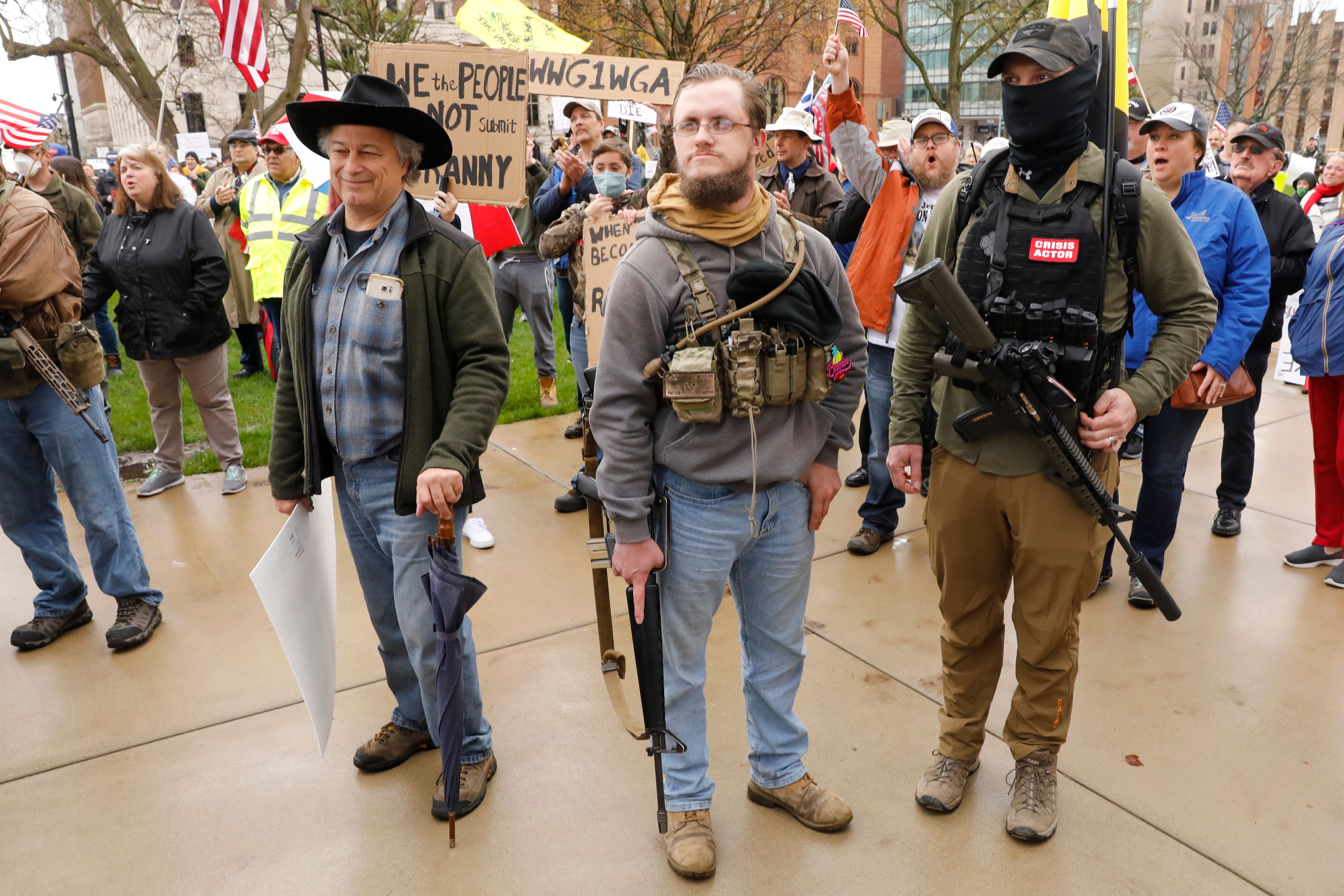 In this image, three men stand with guns 