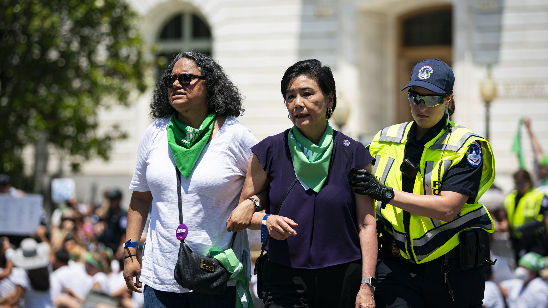 Photo of a U.S. Capitol Police officer holding Judy Chu's arm as Chu and another protester walk arm in arm