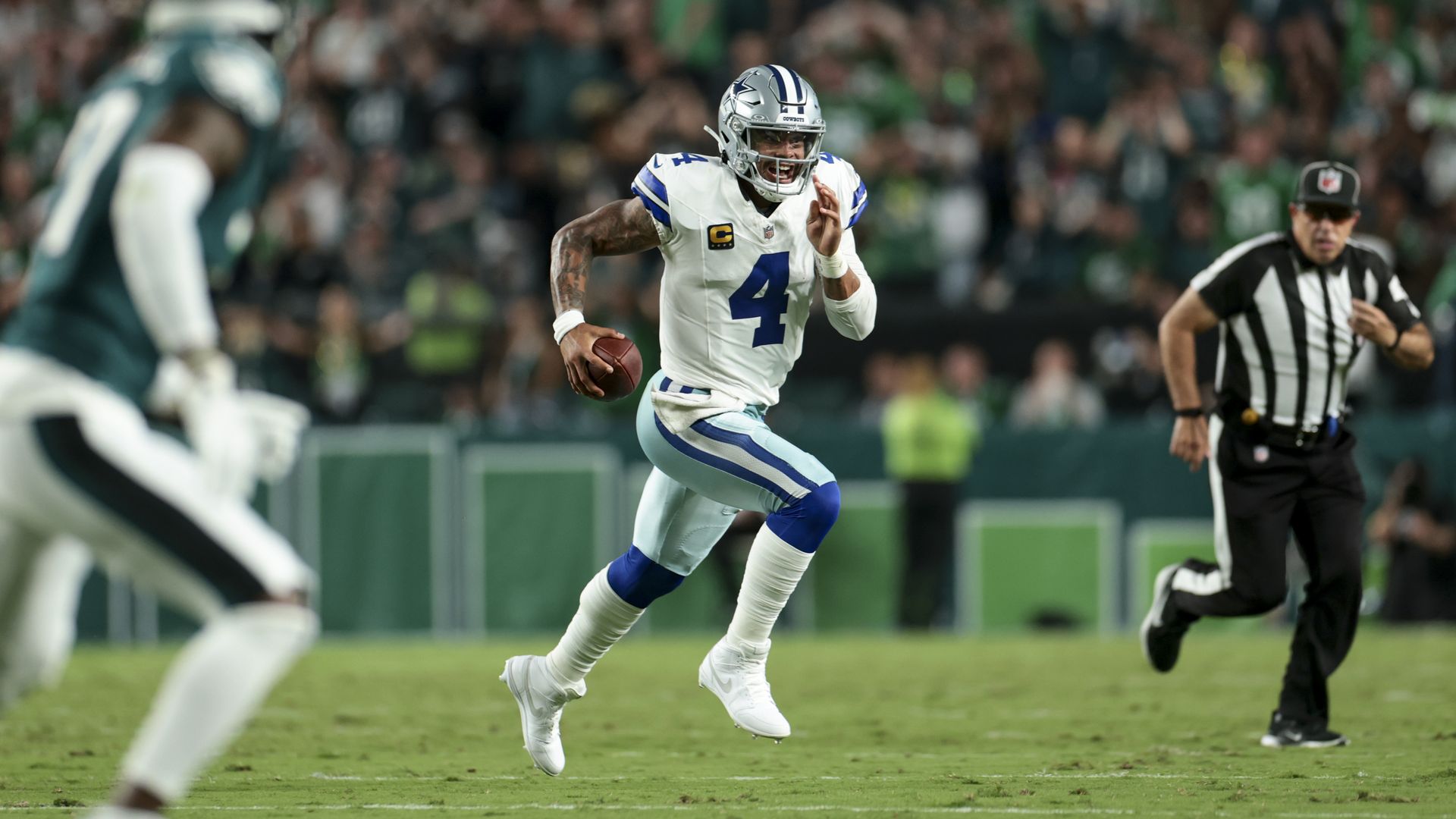 Dak Prescott runs in the middle of the field with a football in his right hand