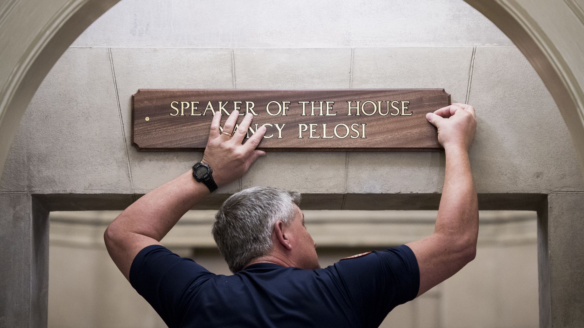 Worker puts up Nancy Pelosi Speaker of the House plaque.