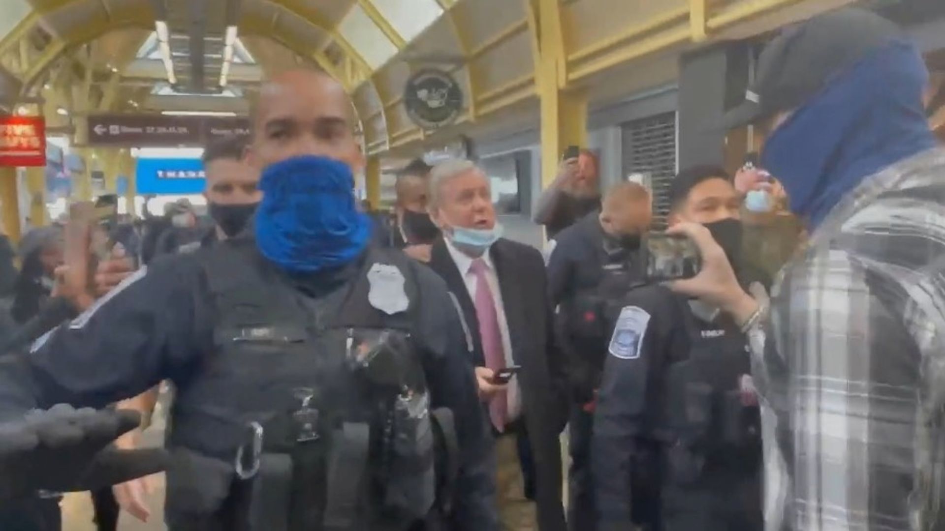 Social media grab shows Sen. Lindsey Graham being escorted by security personnel Friday as Trump supporters berate him at Washington Reagan National Airport.