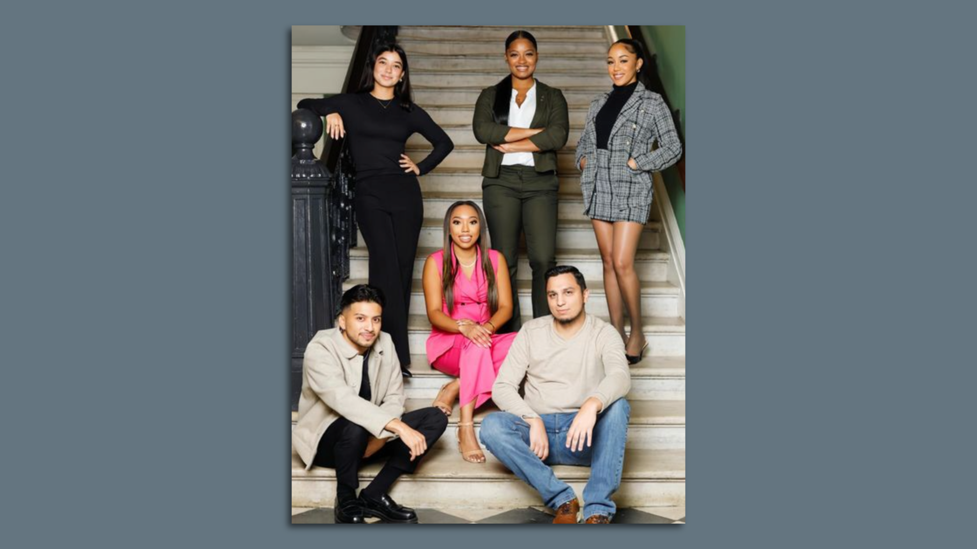 Photo shows multiple people smiling on a staircase.