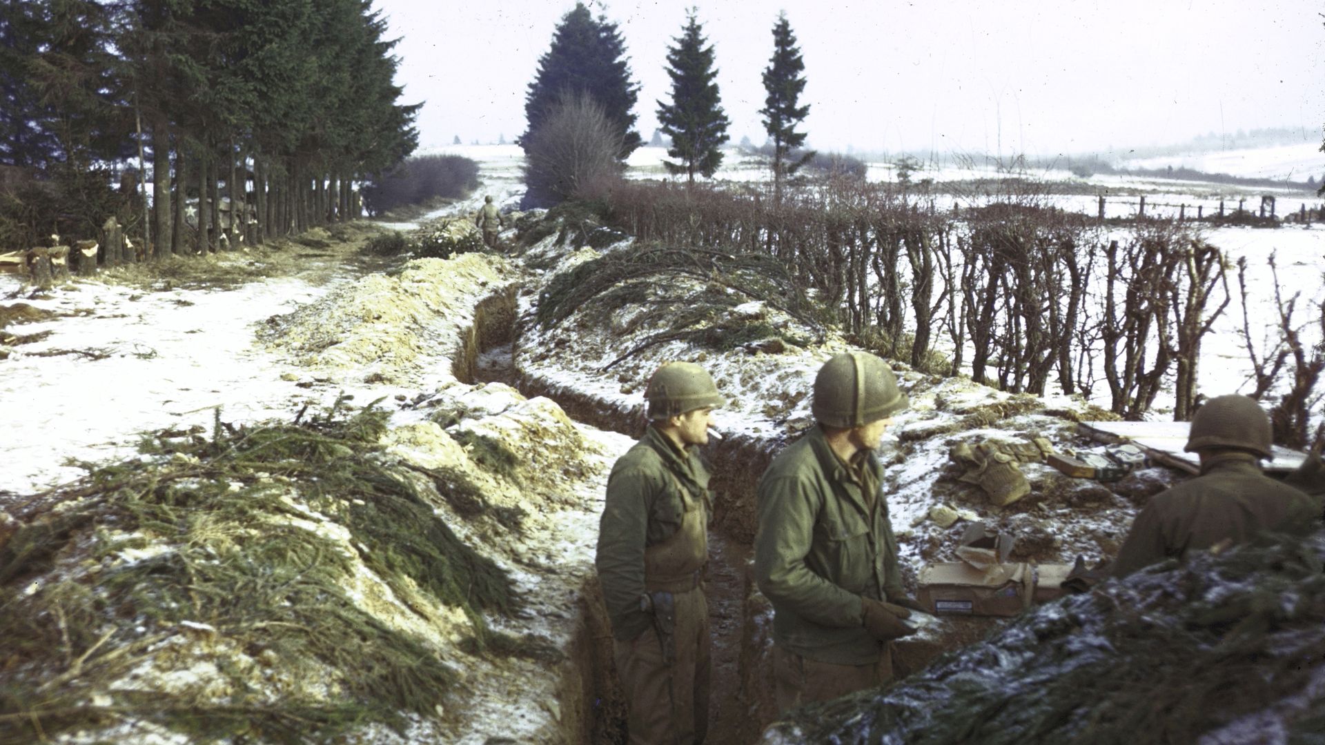 American troops manning trenches along snowy hedgerow in the northern Ardennes Forest during the Battle of the Bulge, the last major German offensive of WWII. 
