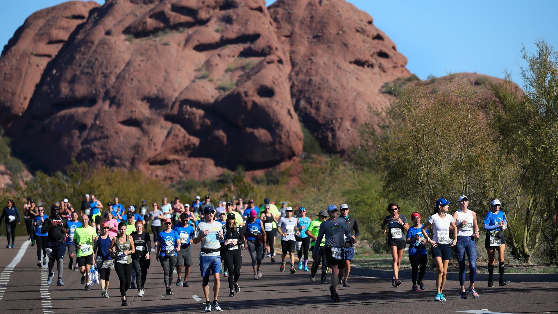 People running near a mountain. 