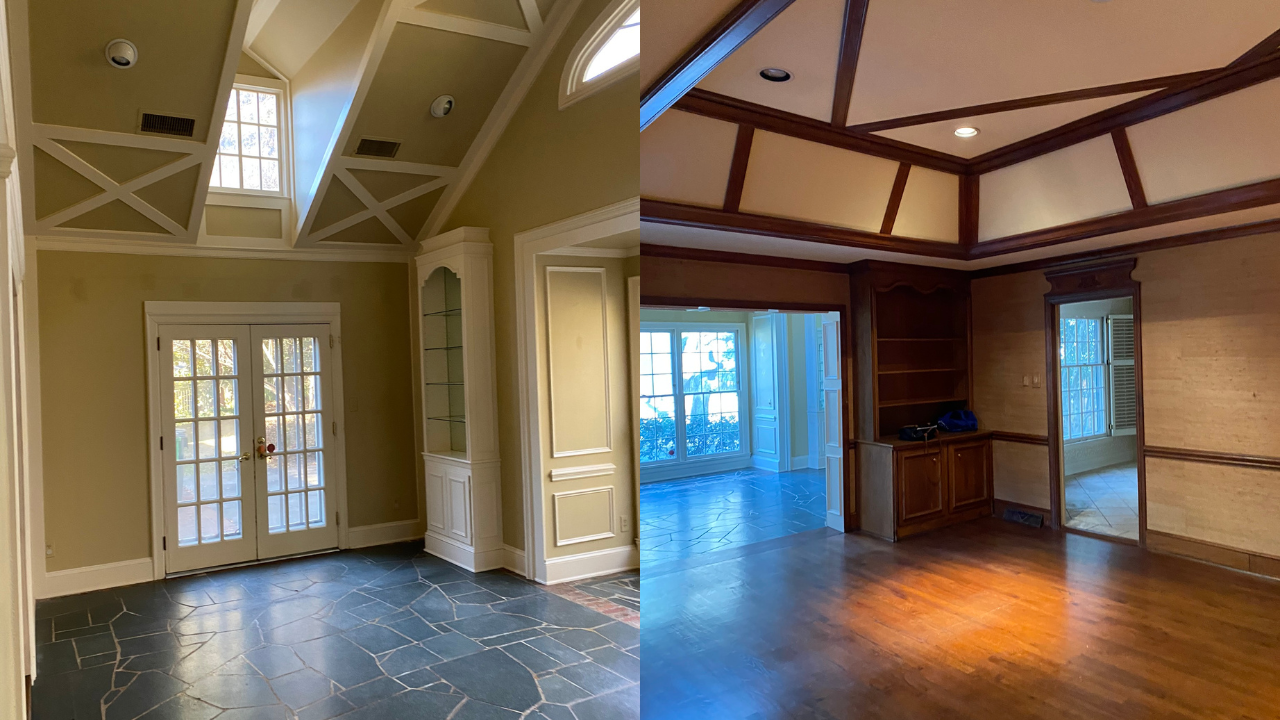 Two adjoining rooms with different flooring and ceiling styles; left has slate tile floor, tall windows, and vaulted ceiling with beams; right has wooden floor, paneled walls, and wooden beams on ceiling.