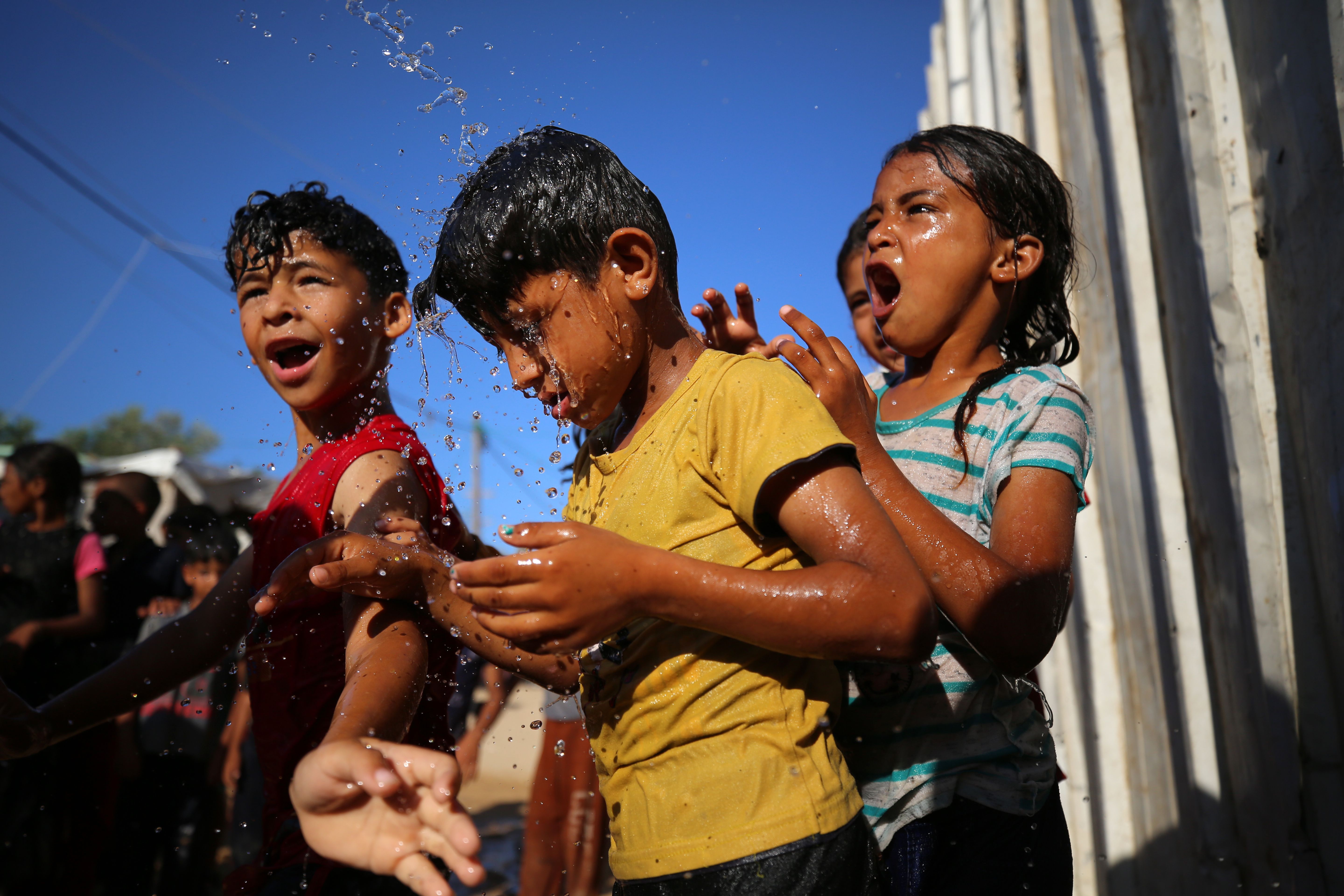 Palestinian children play with water in a slum on the outskirts of the Beit Lahia in the northen Gaza Strip, on July 17, 2023, during a heat wave.