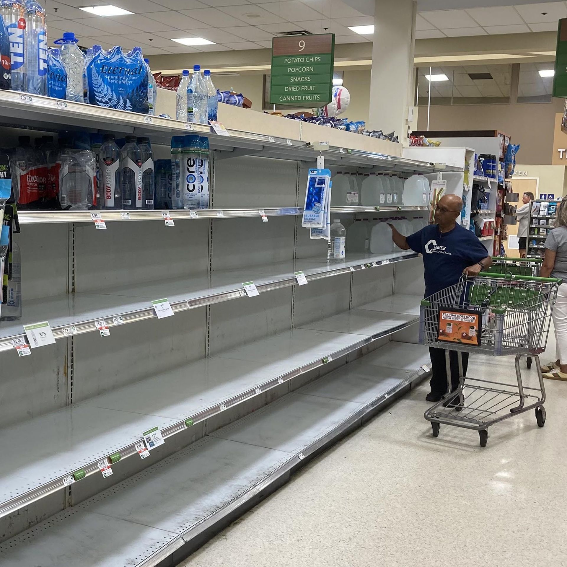 shoppers in a mostly empty aisle of water