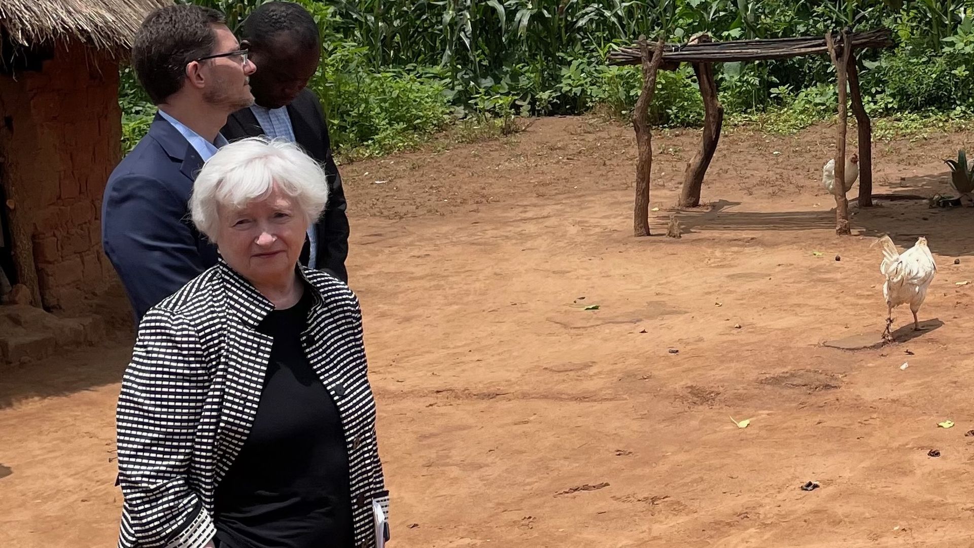Janet Yellen looks into the camera in Africa with a chicken in the background