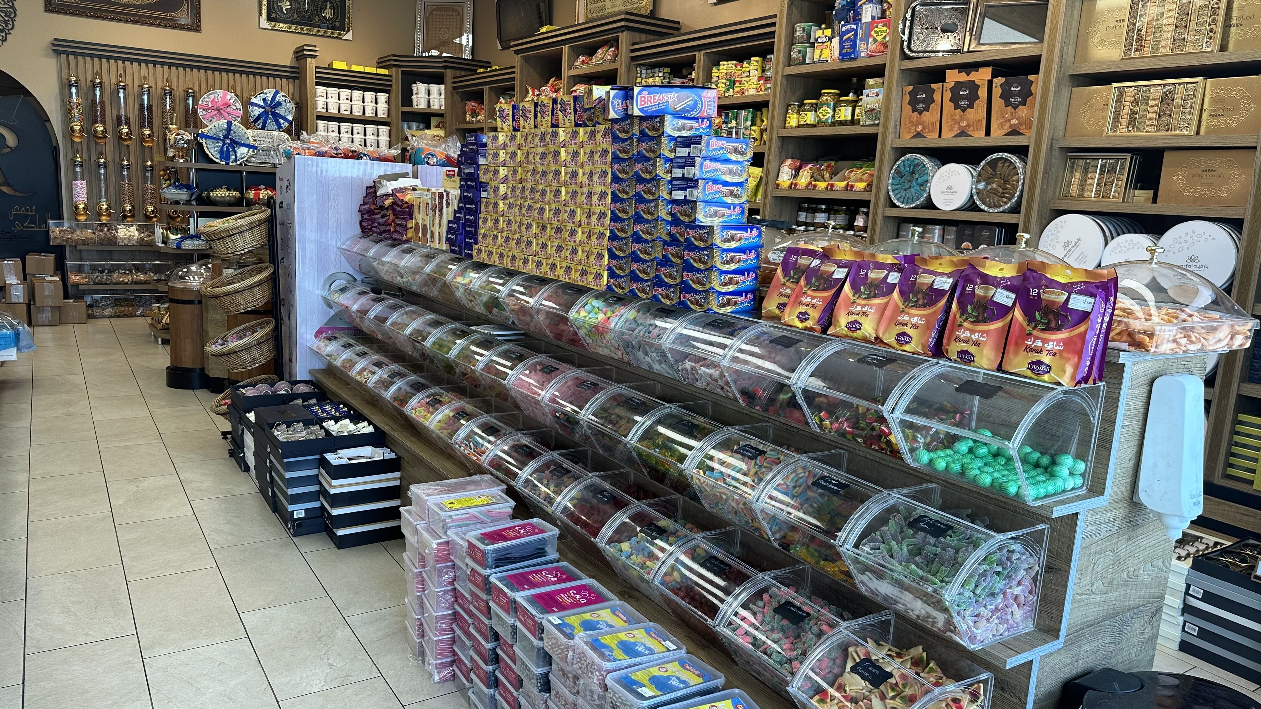 A line of tubs filled with gummy and chocolate candies angles town a store aisle.