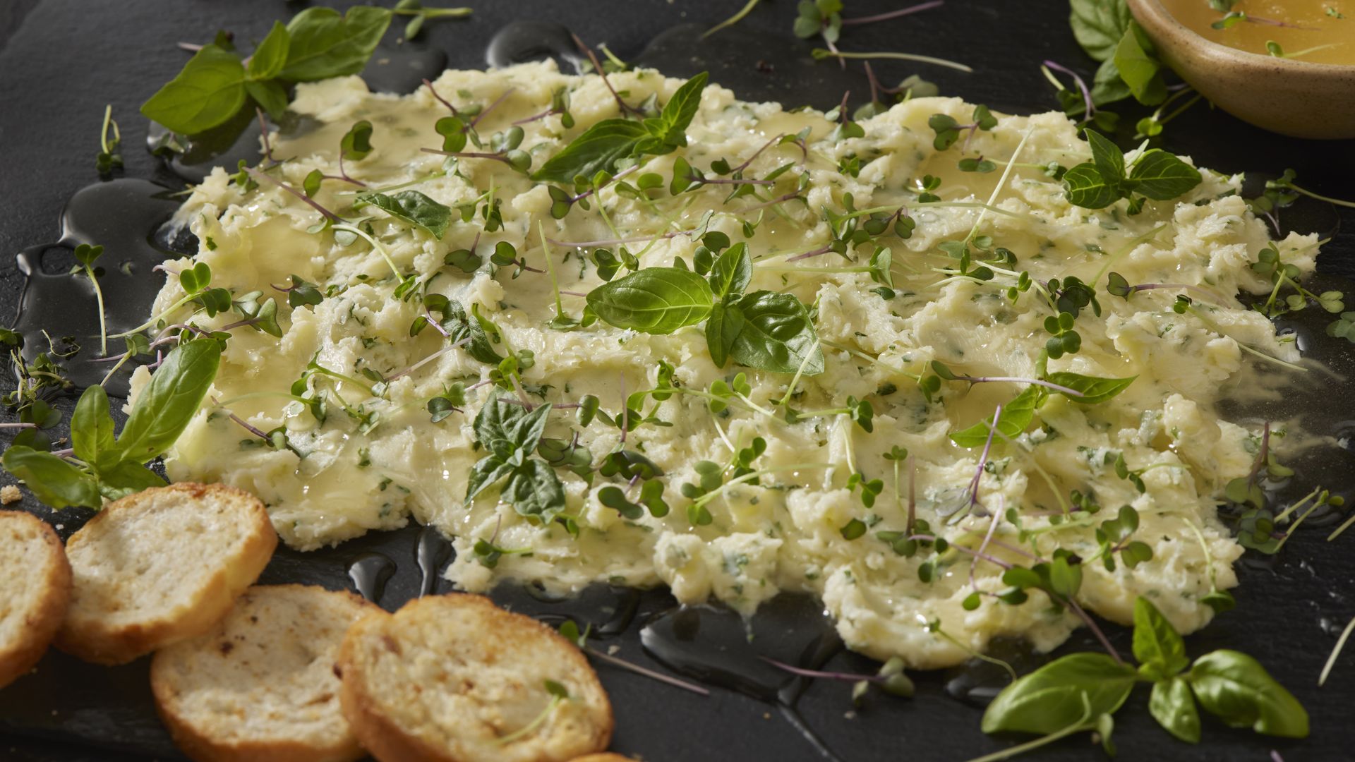 A bunch of butter spread on a slab, topped with microgreens. 