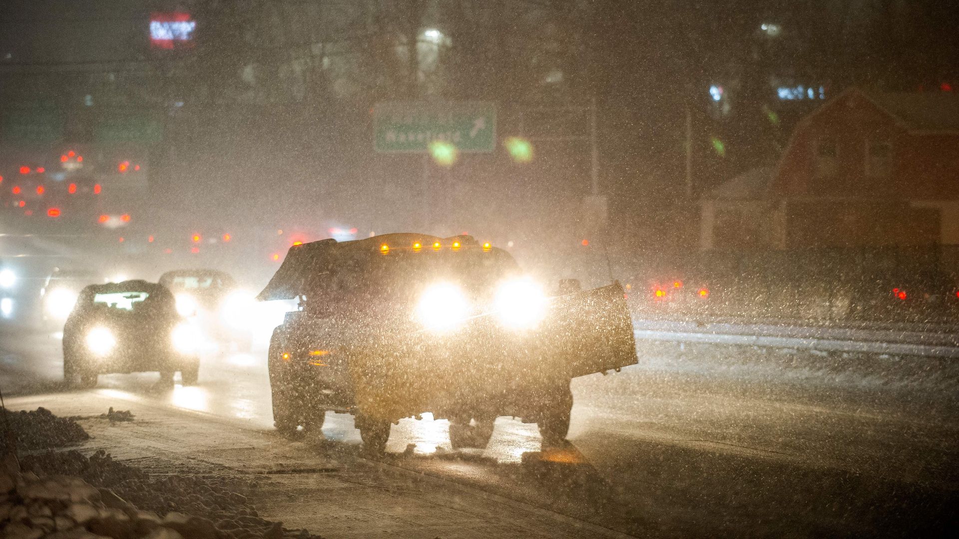 A plow makes it way down US Route 1, throwing sand, as cars are engulfed by snow in the early stages of the second part of Winter Storm Ezekiel in Saugus, Massachusetts on December 2