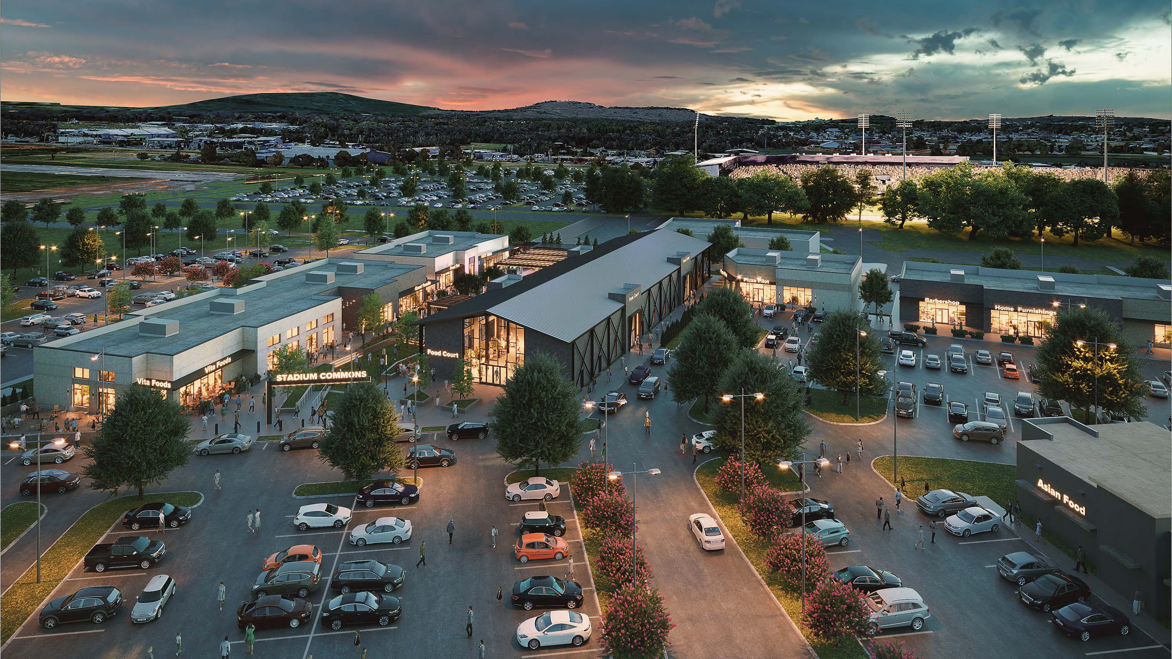 A rendering of a modern mixed-use development at dusk, with a lighted soccer stadium and mountains visible in the background