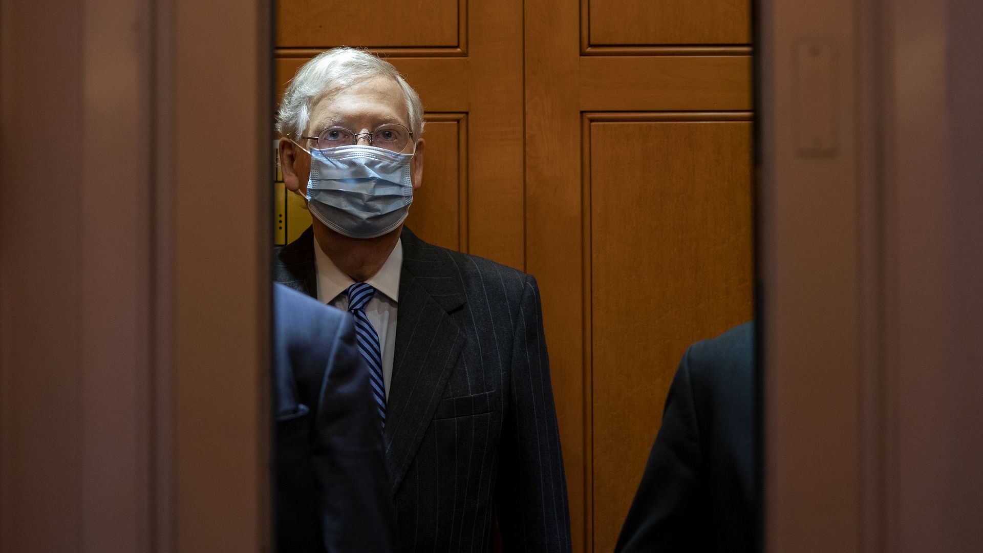 McConnell stands in an elevator while wearing a facemask