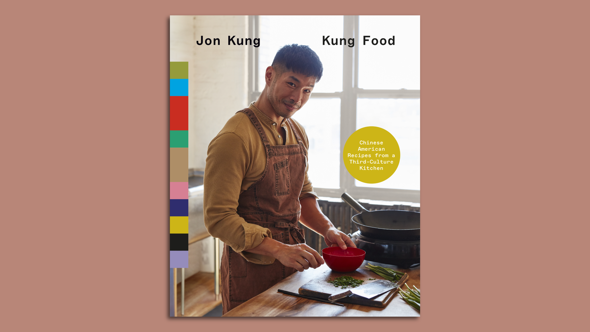 The cover of the cookbook shows Jon posing in front of cooking implements with light coming in through a window behind.