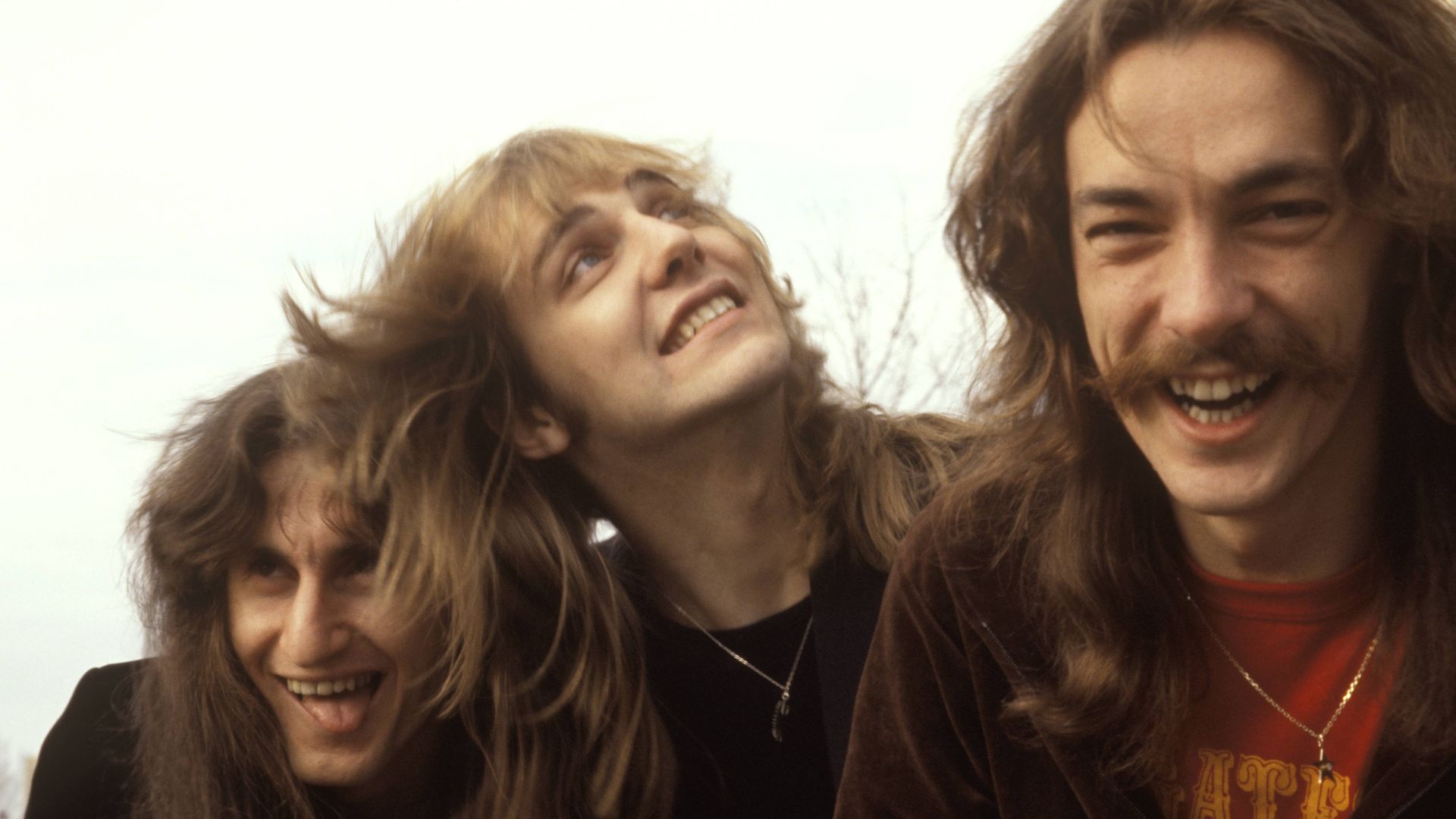 Rush members Geddy Lee, Alex Lifeson and Neil Peart make funny faces and pose for a photo side-by-side.