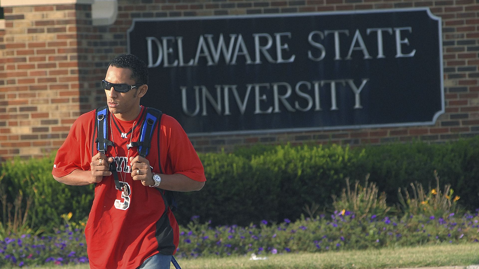 Picture of a student walking in front of a sign with the delaware state university name