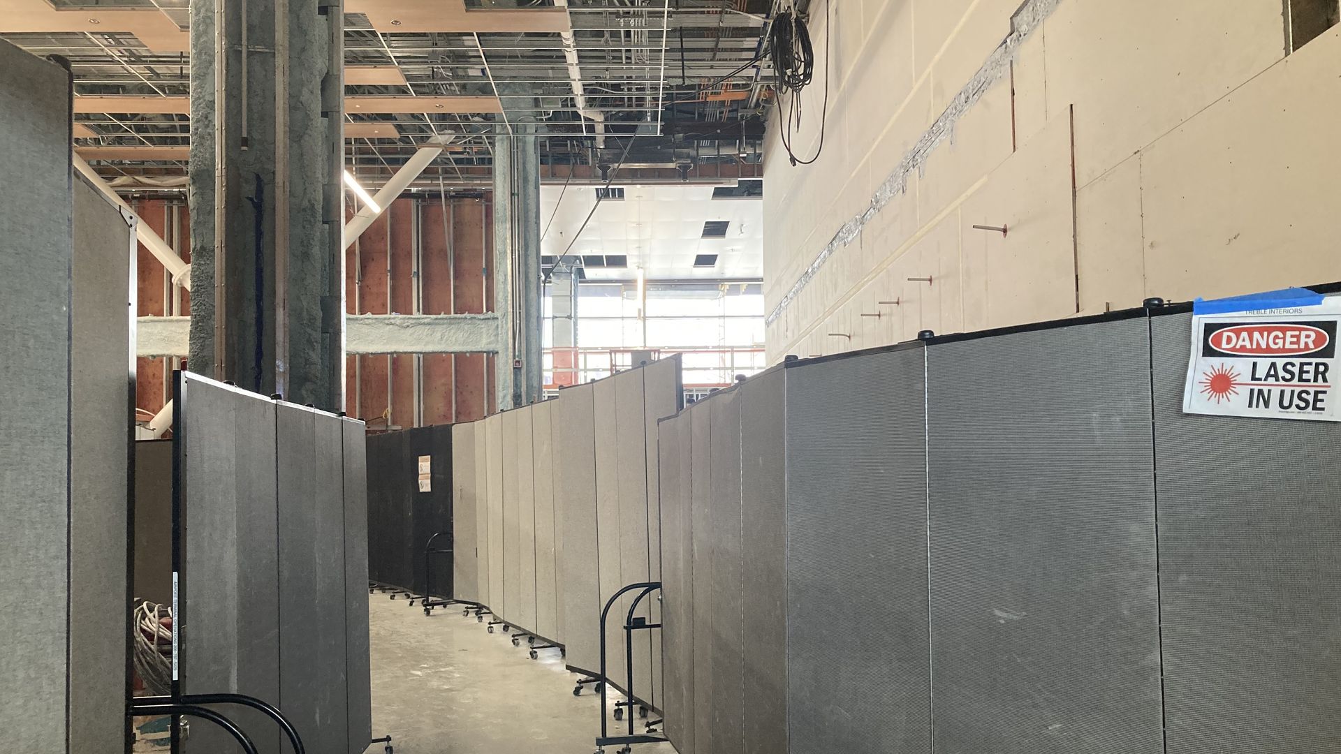 Ceilings and walls are exposed in an  area that is under construction at an airport. 