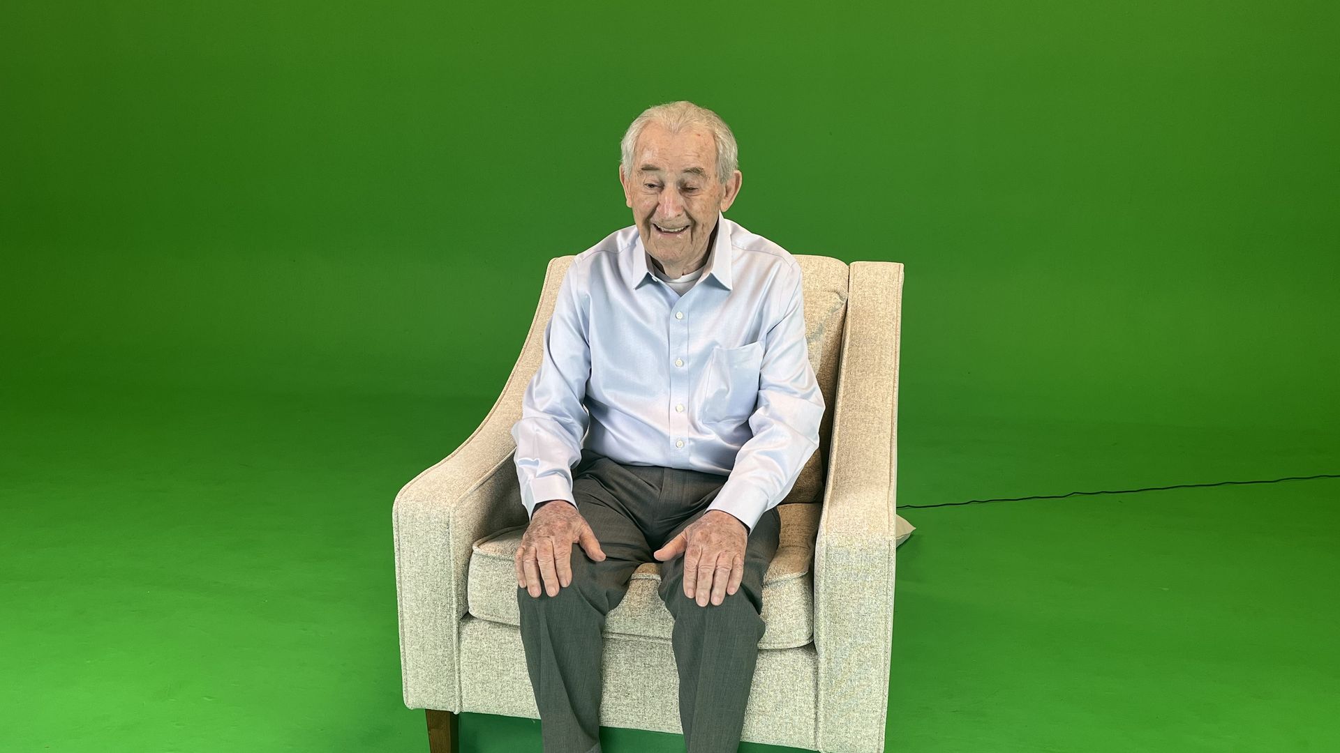 Holocaust survivor David Schaecter sits in front of a green screen as part of a holographic museum exhibit.